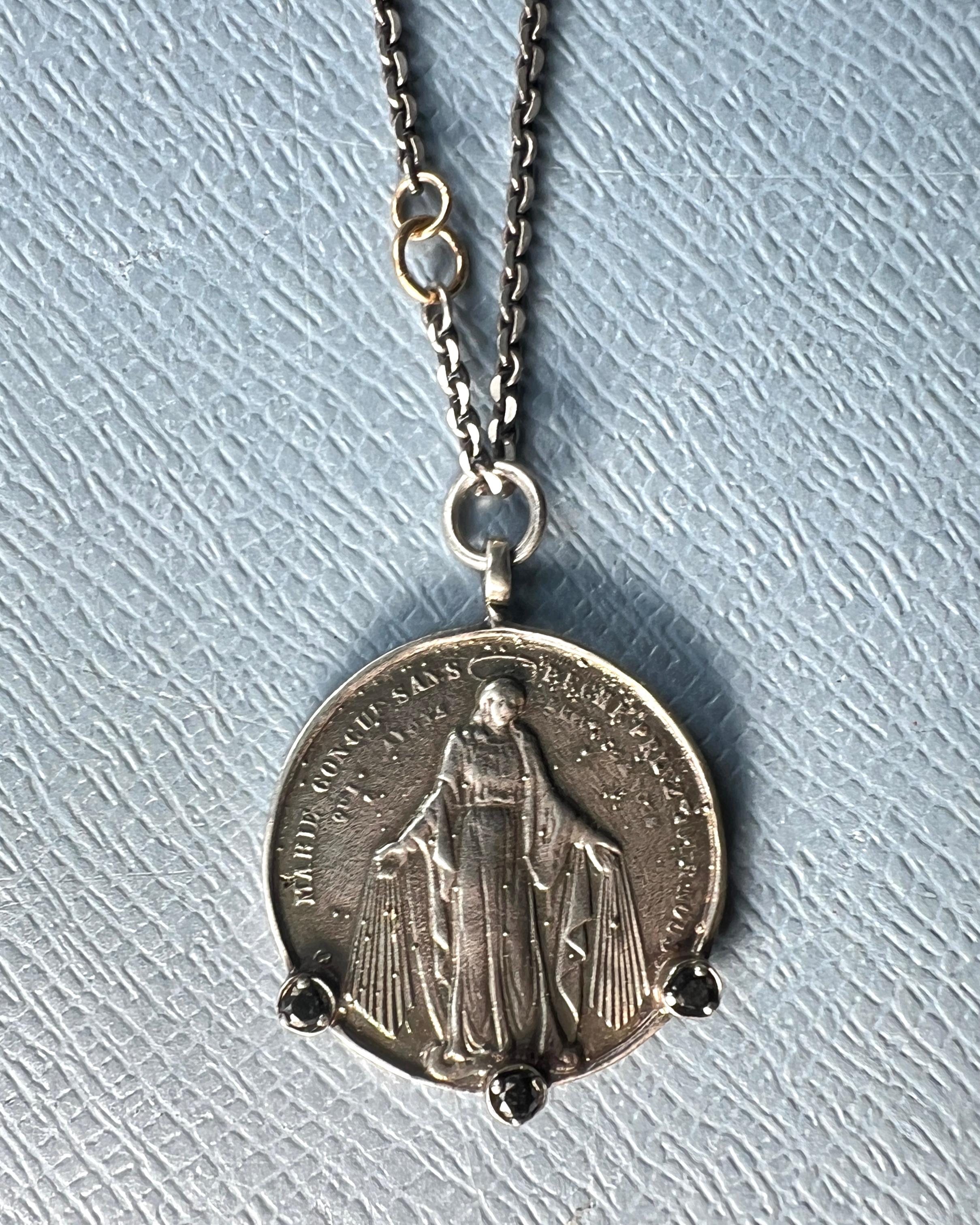 Collana a catena con medaglia di diamanti neri della Vergine Maria A. Silver

Progettista: J Dauphin

Lunghezza: 29 pollici

Questa medaglia miracolosa in argento, realizzata a mano, raffigura la Vergine Maria su un lato e San Joseph con in braccio