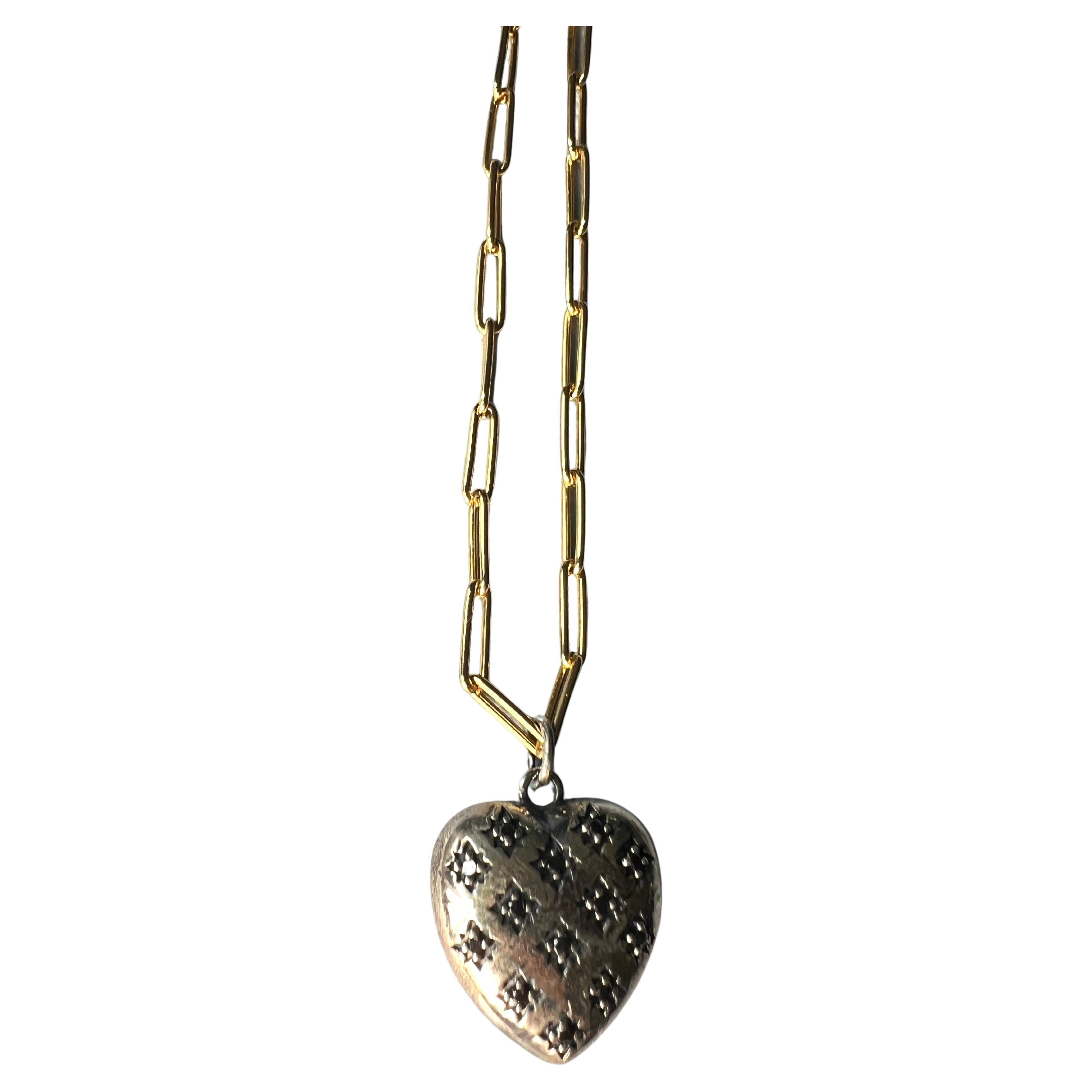 Ce collier symbolique de J Dauphin présente un pendentif en forme de cœur bouffant d'inspiration victorienne réalisé en argent massif et incrusté de diamants noirs naturels. Suspendue à une chaîne de 28 pouces en laiton plaqué or, cette pièce mêle