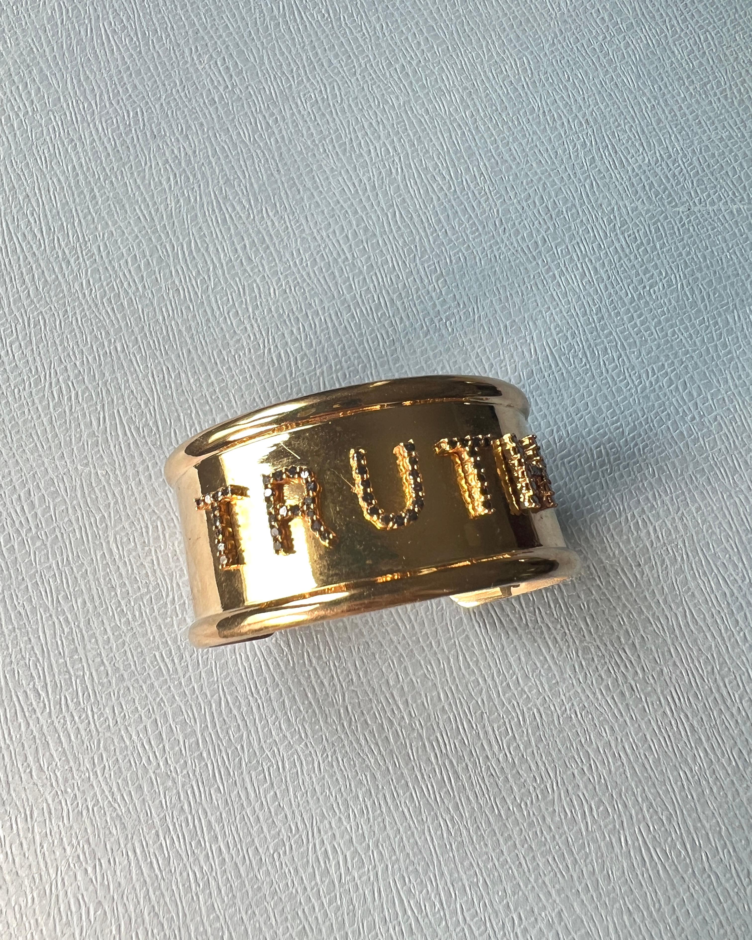 Black Diamond “TRUTH” Cuff Bracelet in 14k Gold-Plated Brass – Kabbalistic Spiritual Jewelry

This bold cuff bangle is crafted in 14k gold-plated brass and features the word “TRUTH,” each letter formed in natural black diamonds. Designed by