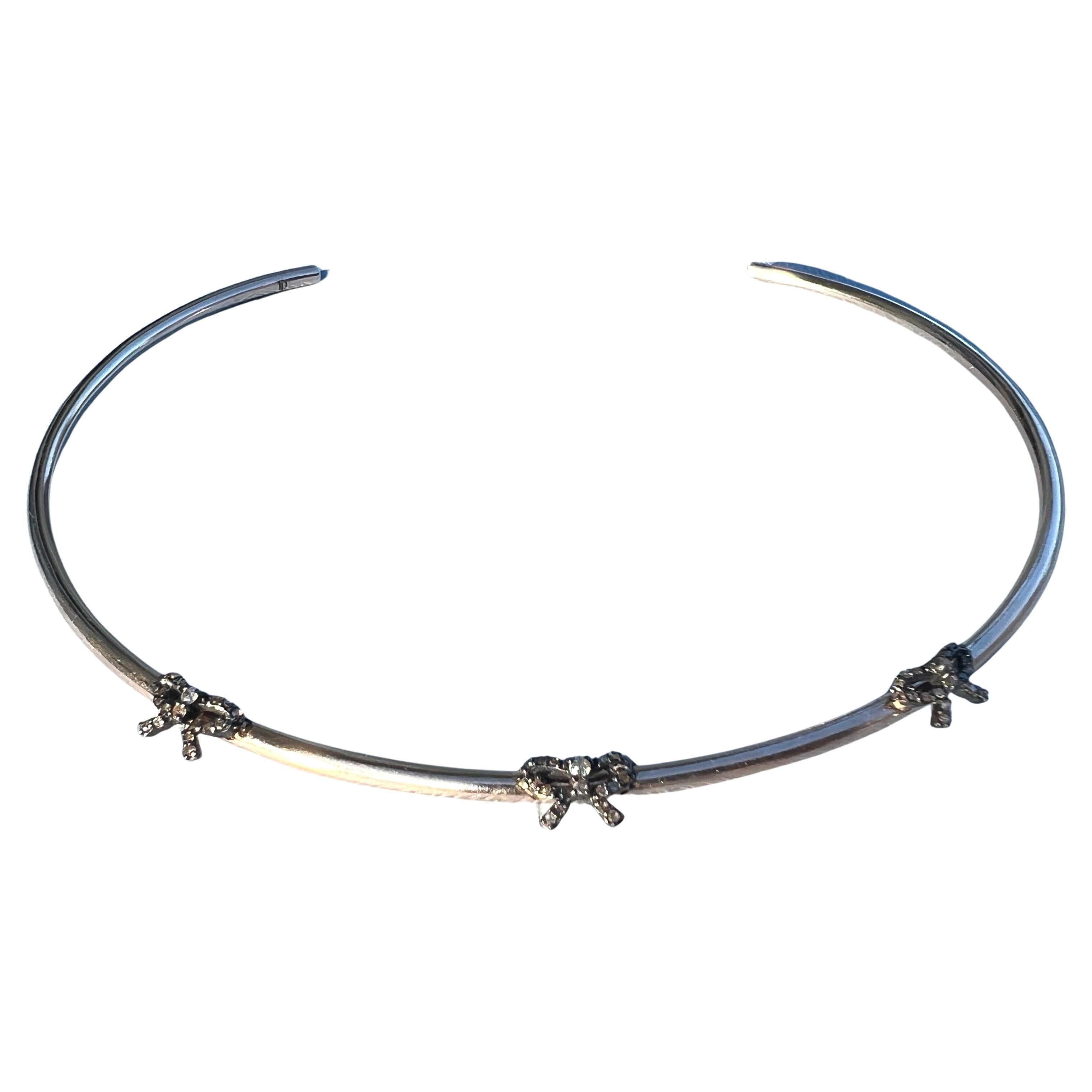 Tour de cou victorien avec nœud en diamant brut 

Ce bracelet de cou symbolique de J DAUPHIN présente trois nœuds sculpturaux de style victorien ornés de diamants naturels bruts, sertis sur une bande ouverte de style tour de cou fabriquée en laiton
