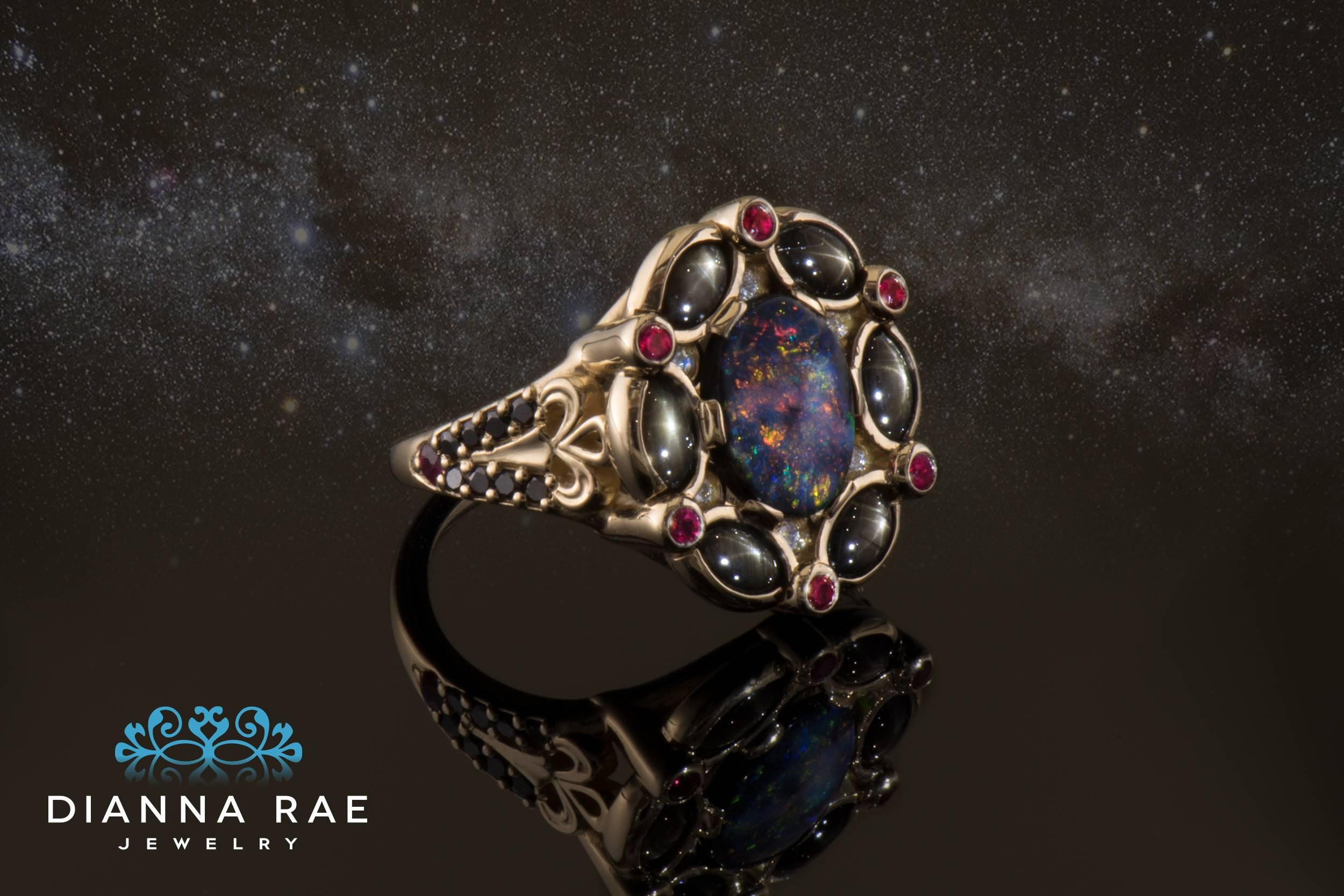 Black Opal Ring Surrounded by Black Star Sapphires, Diamonds and Burmese Rubies

This Dianna Rae Original is truly a one-of-a-kind.  Named 