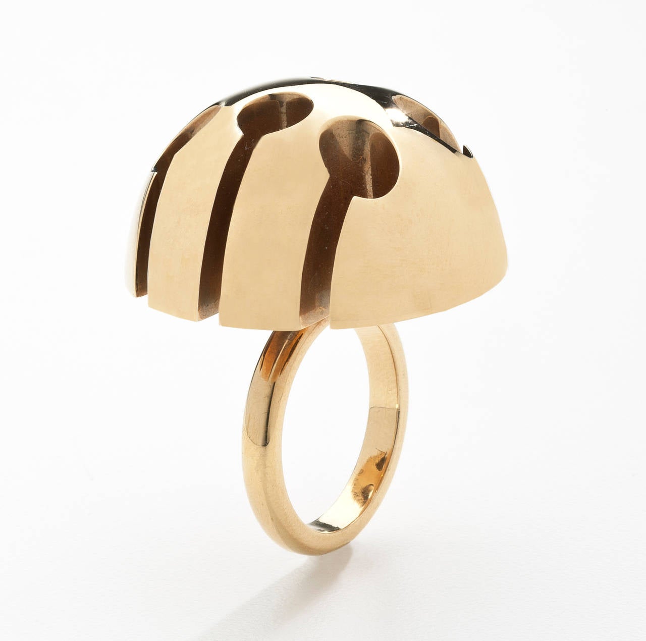 An abstract designed gold ring by Italian sculptor Arnaldo Pomodoro (born 1926).  The 18 karat gold ring is a large demi sphere that looks like a photo of the surface of the moon.   The piece was originally part of the jewelry collection