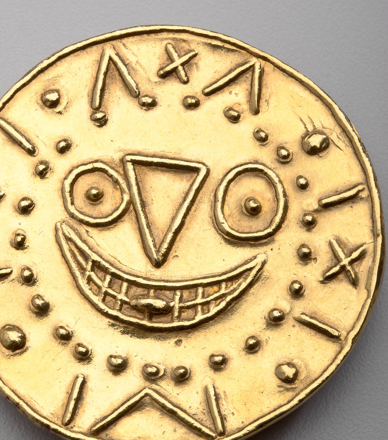 An 18 karat gold pendant/ brooch by Pablo Picasso in its original box.  The  pendant/brooch is designed as a clock with a face in the center and the tongue sticking out.  Picasso titled the medallion appropriately, 