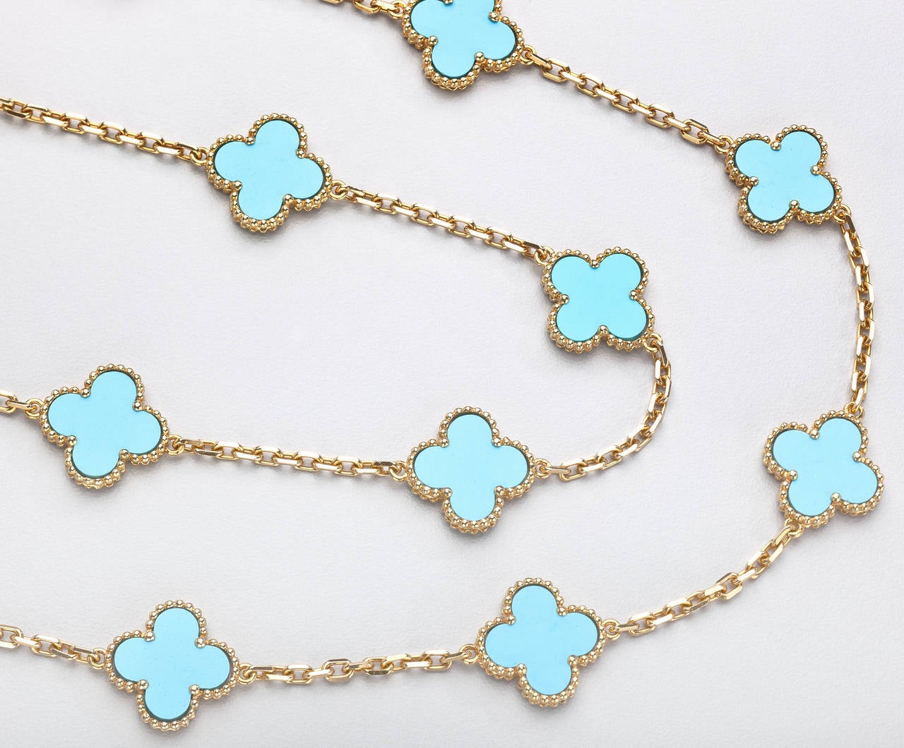 An 18 karat gold and turquoise oval link chain necklace spaced by 20 double-sided turquoise clovers edged in rope-twist gold. The turquoise is a striking contrast to the yellow gold.   A signed and authenticated necklace in the iconic Alhambra