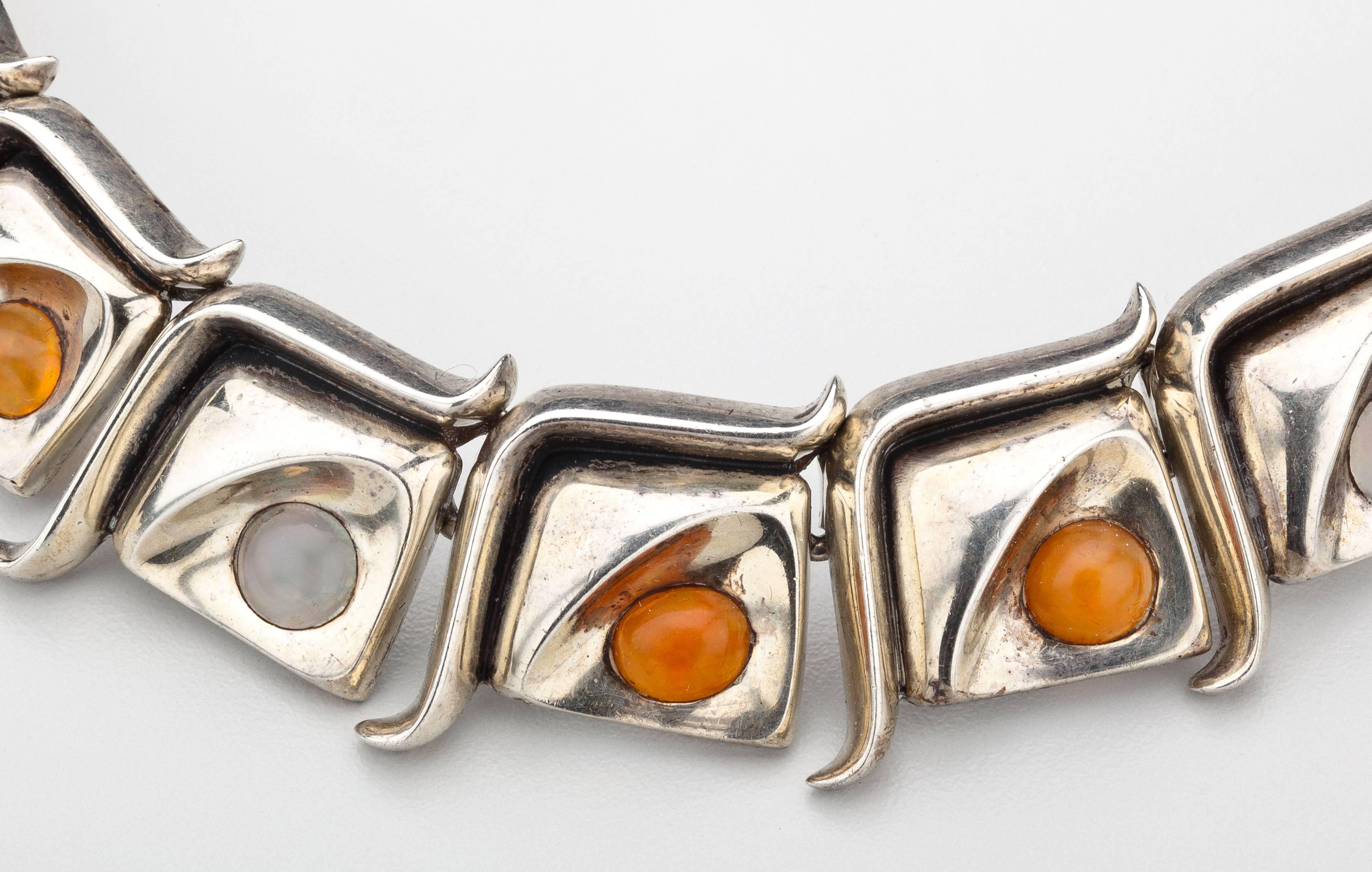 A necklace by Mexican master silversmith, Antonio Pineda, in sterling silver and  opal.  Antonio designed this necklace to feature ten asymmetrical panels each accented with either a fire or white cabochon opal.   Antonio did from time to time use a