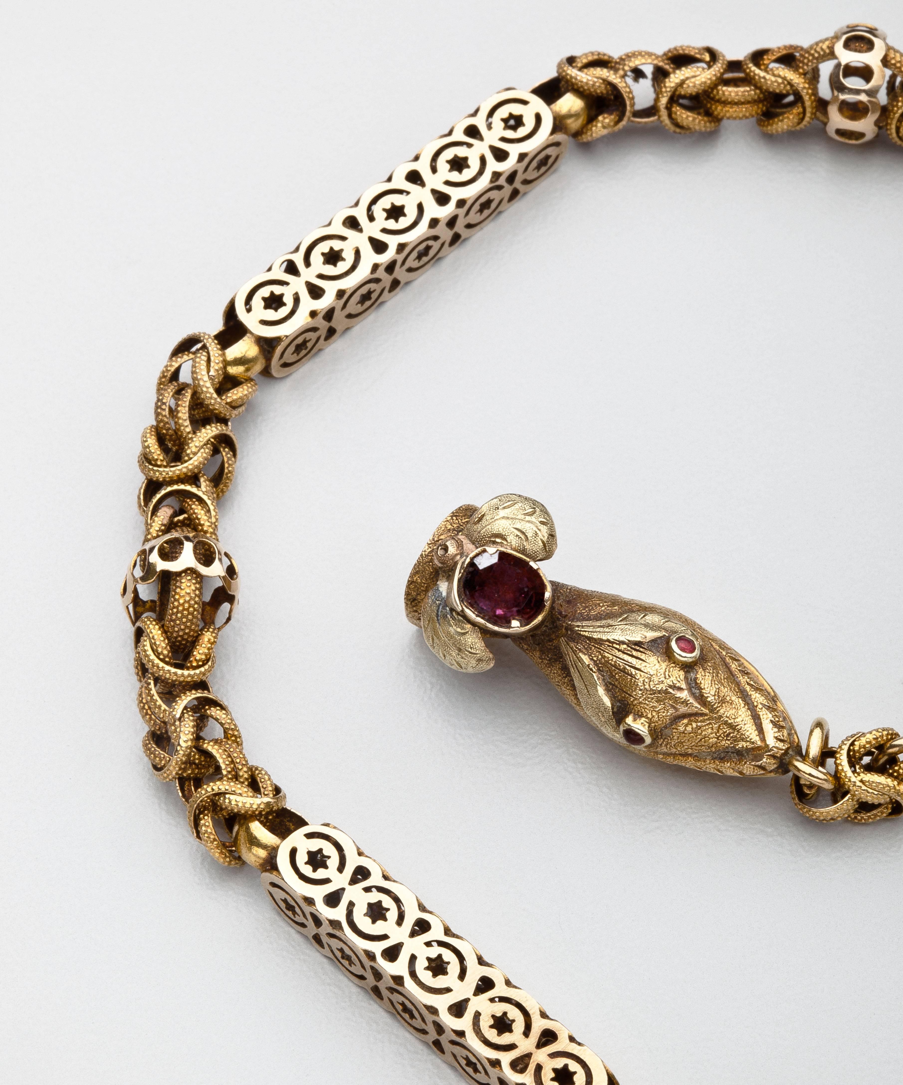 A long four foot antique  gold chain in the Gothic revival style with Moorish overtones of design.  The 15 karat gold chain culminates in  a snake head clasp accented with garnet eyes.    