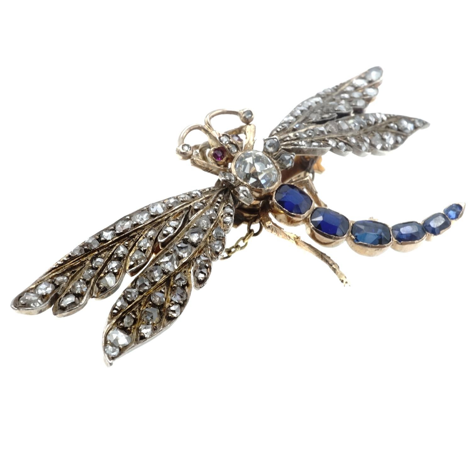 The dragonfly is crafted in 14 karat rose gold and silver featuring an old european cut diamond on the body and rose cut diamonds on moveable wings mounted on springs.  The tail is enhanced with 6 sapphires and the eyes are set with rubies.  Weighs