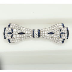 Broche vintage Art déco en platine, sertie de saphirs et de diamants, en forme de nœud