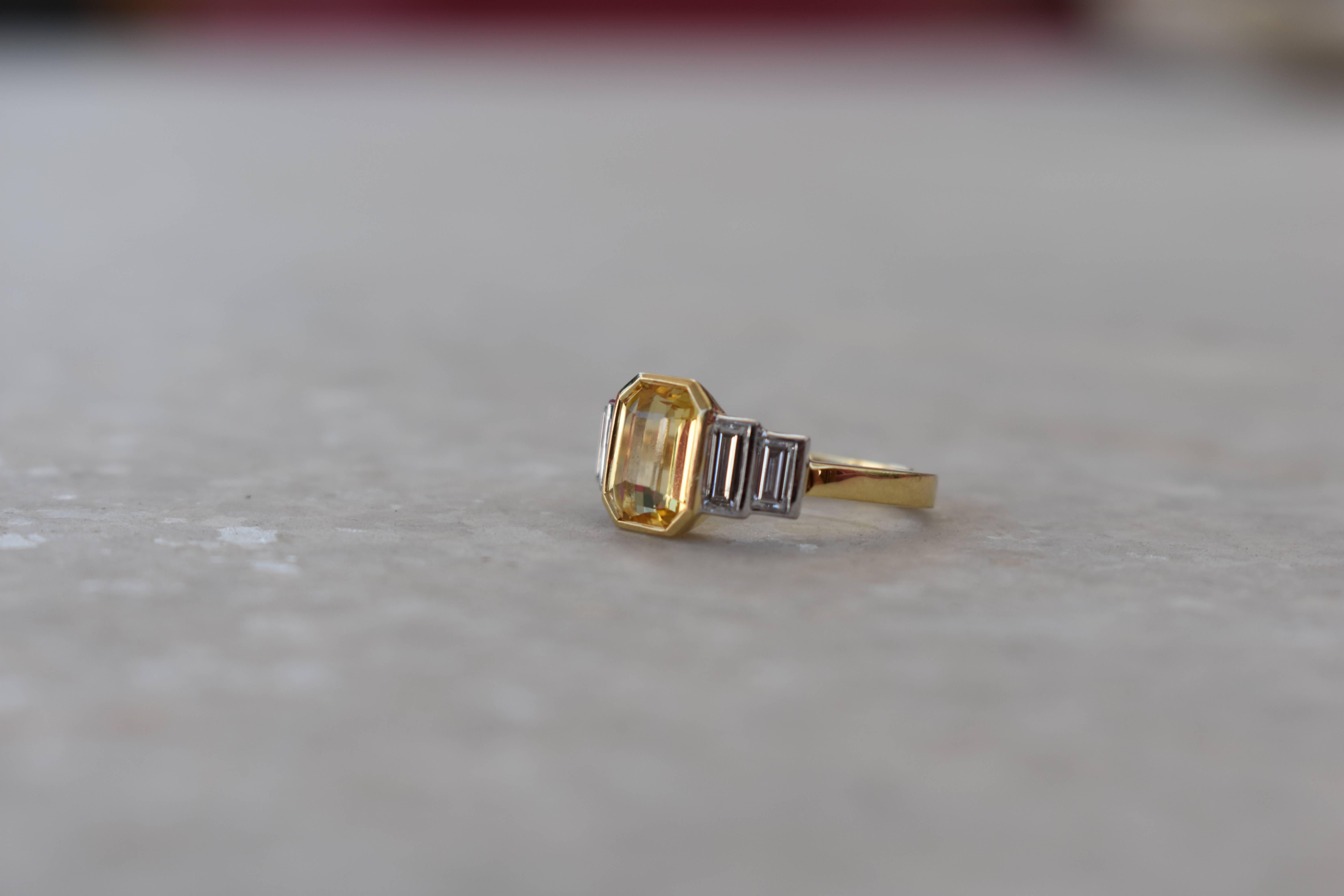 A sophisticated Sri Lankan yellow emerald cut sapphire and baguette diamond ring. 18 karat yellow and white gold surround the yellow, no heat sapphire, and tapered baguette diamonds. Perfect as a dress ring or engagement ring. Comfortable to wear as