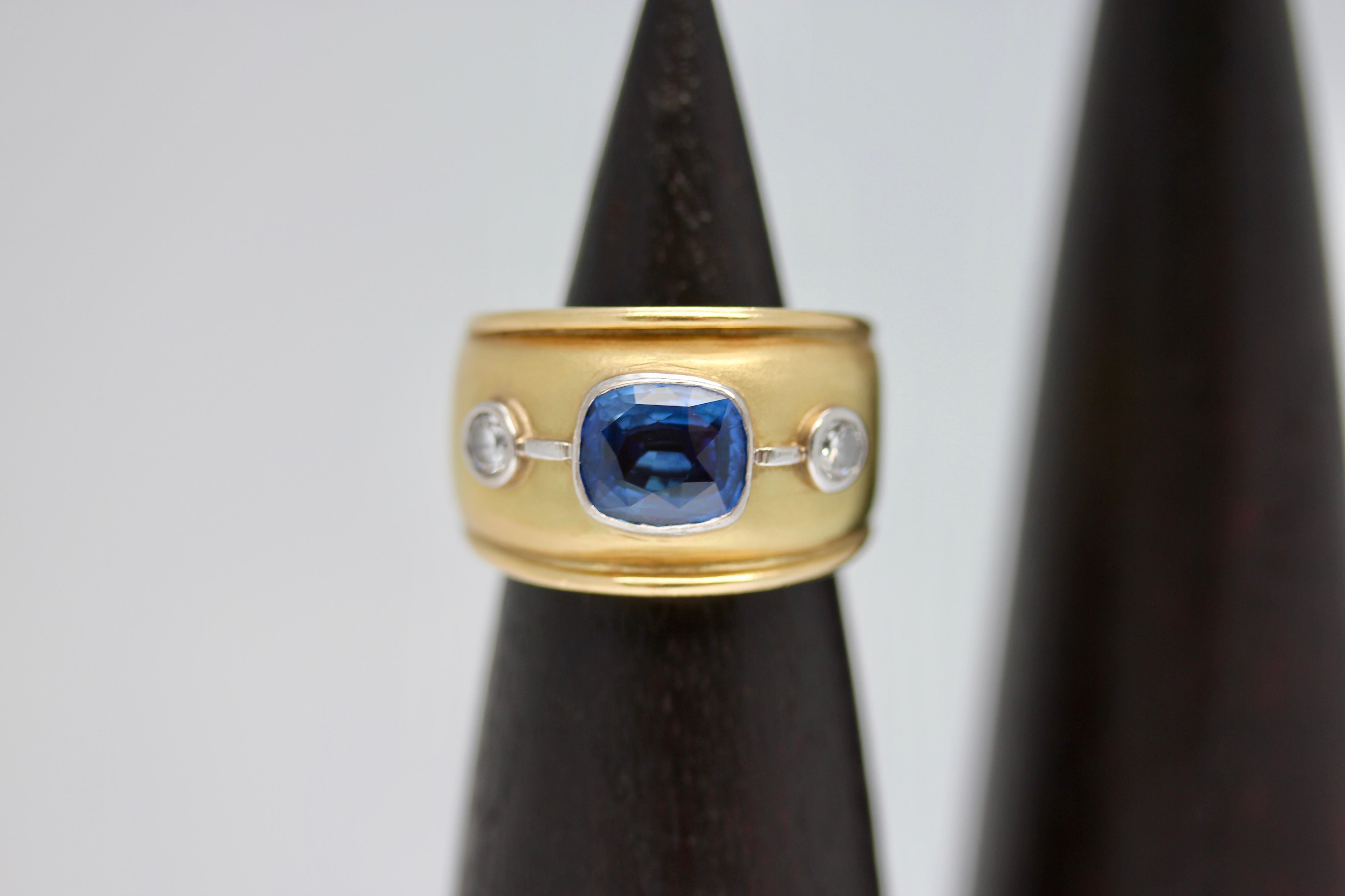 Stunning Sri Lankan blue sapphire and white diamond 18 karat yellow gold cocktail ring. A beautiful and modern design featuring a blue sapphire and two round diamonds set into a comfortable and elegant design. 

This item is made bespoke, lead time