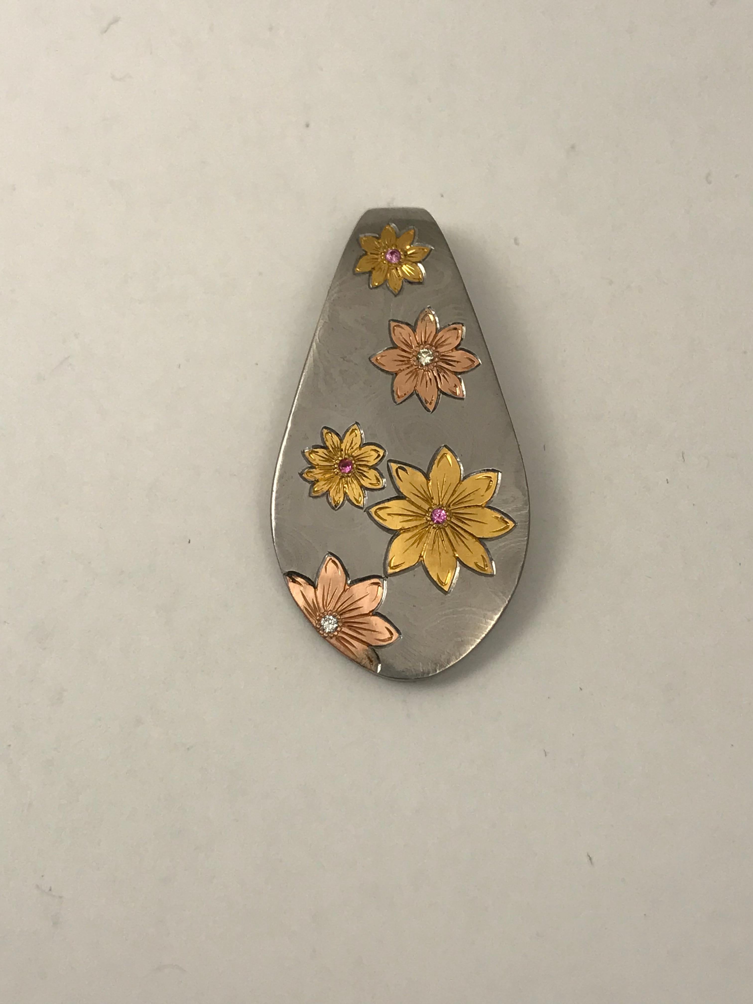 Damascus Steel Pendant with Rose Gold & 24K Gold Flowers

This is a beautiful pendant made of Damascus Steel with 24 karat gold inlays. This is difficult to do because I have to cut out the pattern into the steel then hammer a sheet of 24k gold into