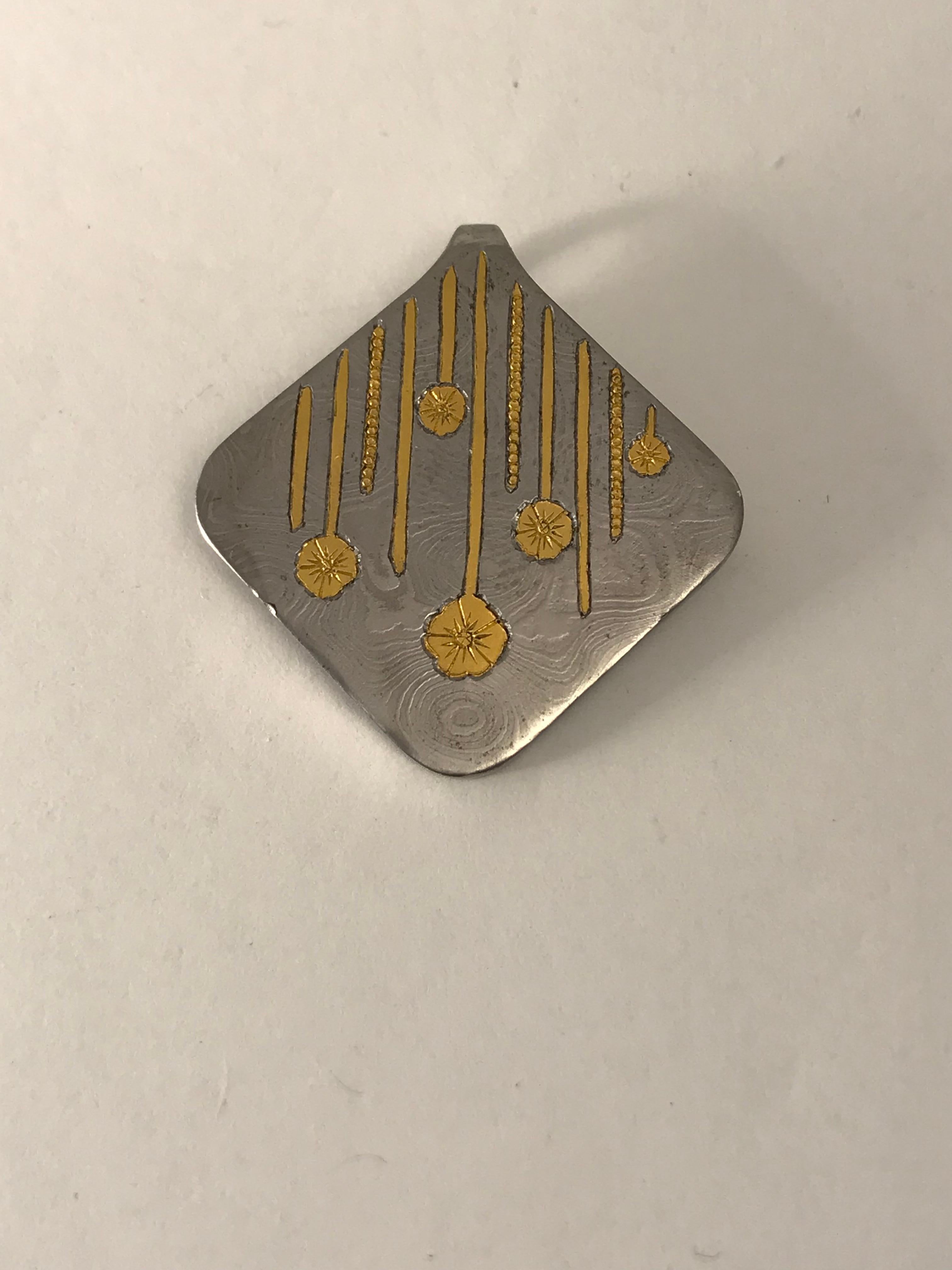 This is a beautiful pendant made of Damascus Steel with 24 karat gold inlays. This is difficult to do because I have to cut out the pattern into the steel then hammer a sheet of 24k gold into the shape then engrave the details. 

The gold will NOT