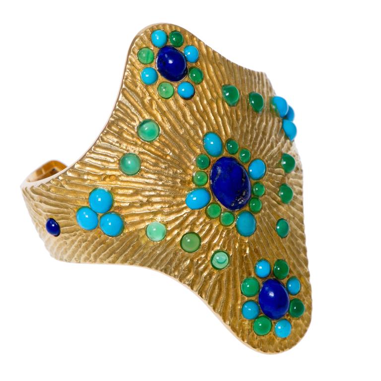 A vintage, chrysoprase, lapis lazuli, turquoise and 18 karat textured yellow gold quatrefoil cuff, by Boucheron, c. 1970.
This highly collectible cuff is signed Boucheron Paris, numbered and has French hallmarks. 

It is perfectly representative of