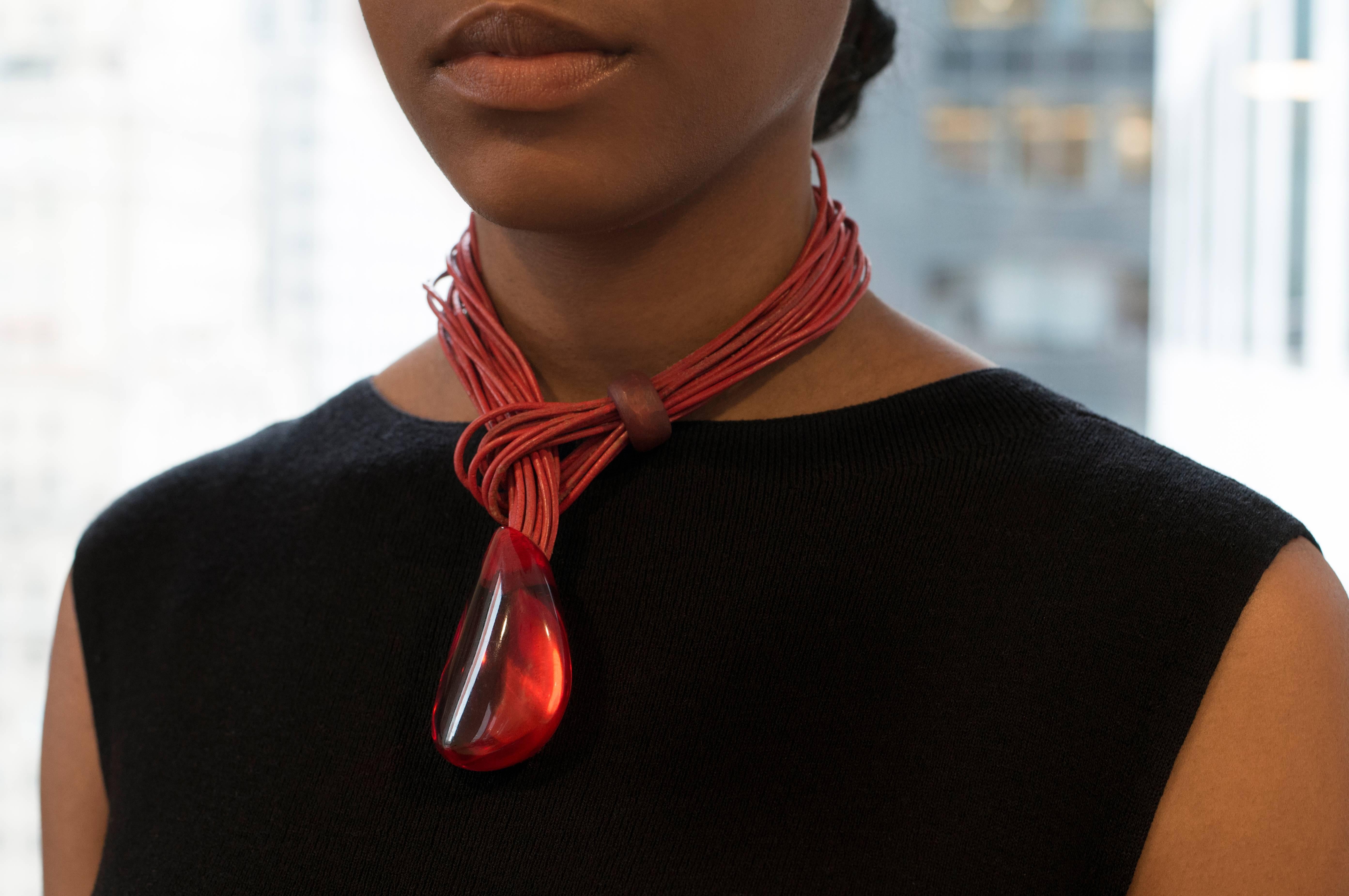 A red leather and resin pendant necklace by Catherine Noll.  In her artistic prime, during the 1970s, Noll created nature-inspired pieces in bold organic shapes, often using natural materials such as horn, bone, wood and stone. She had a wide circle