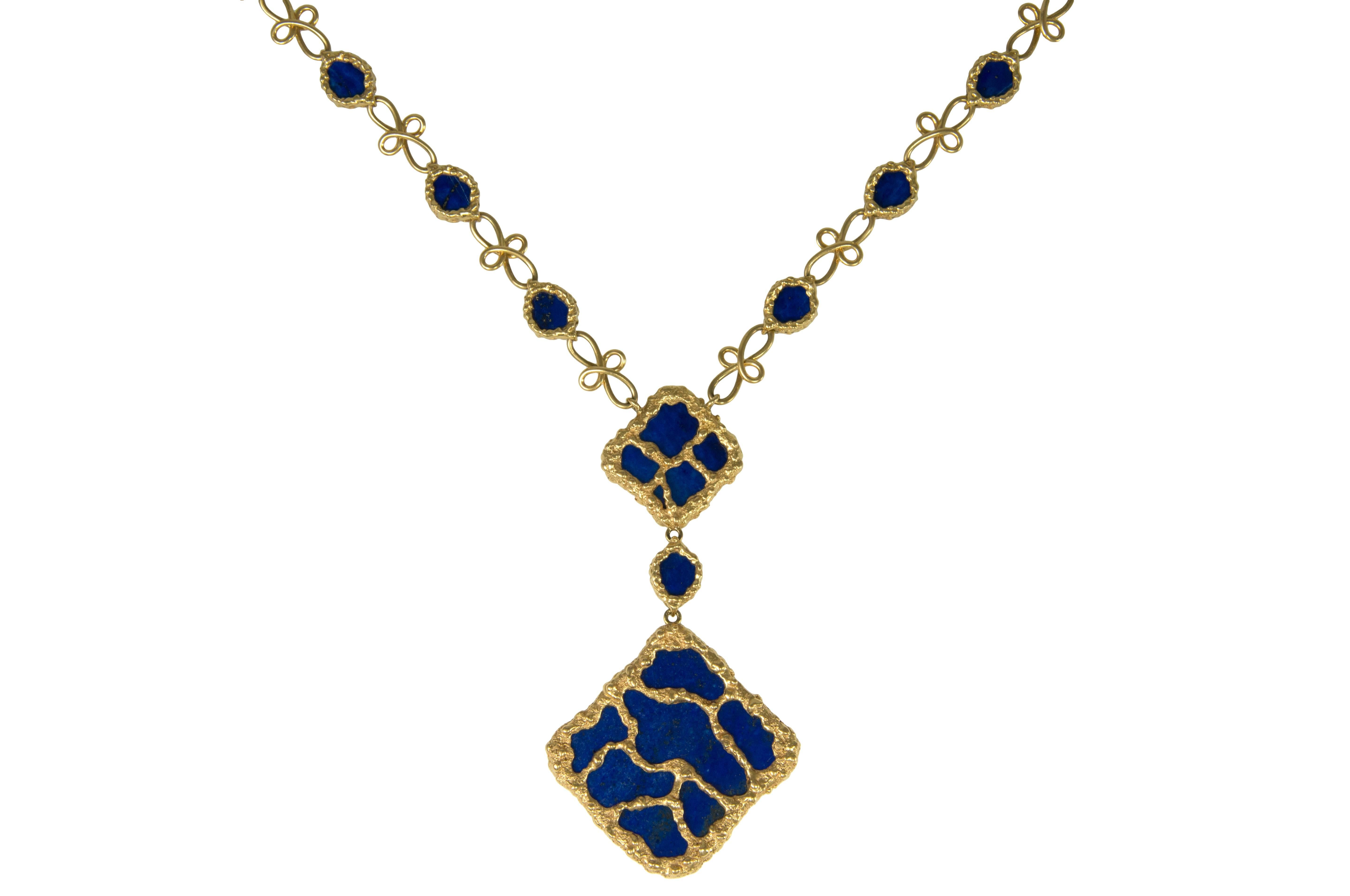 A French-made organic design chain and pendant necklace from the 1970s. The necklace is made of 18 karat textured gold encased lapis buttons, with floral links chain and a lapis lazuli pendant with textured gold inserts., c. 1970. We believe this
