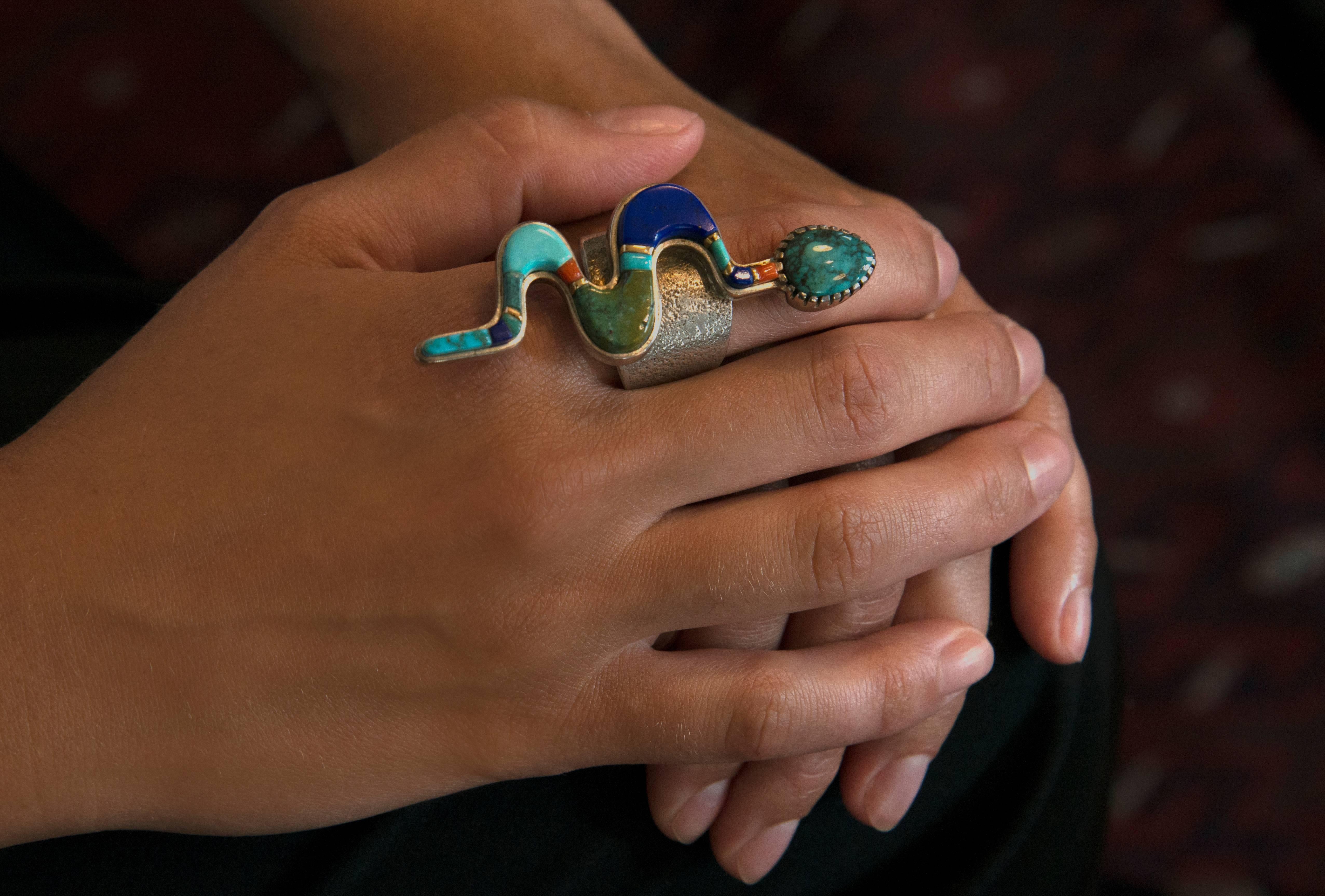 A silver, tufa-cast snake ring with inlaid turquoise, lapis lazuli, coral and six 18k gold spacers, by Verma Nequetewa, SONWAI, 2013. Size 11 1/2. 

This ring looks most striking on the middle finger. It also can be sized.