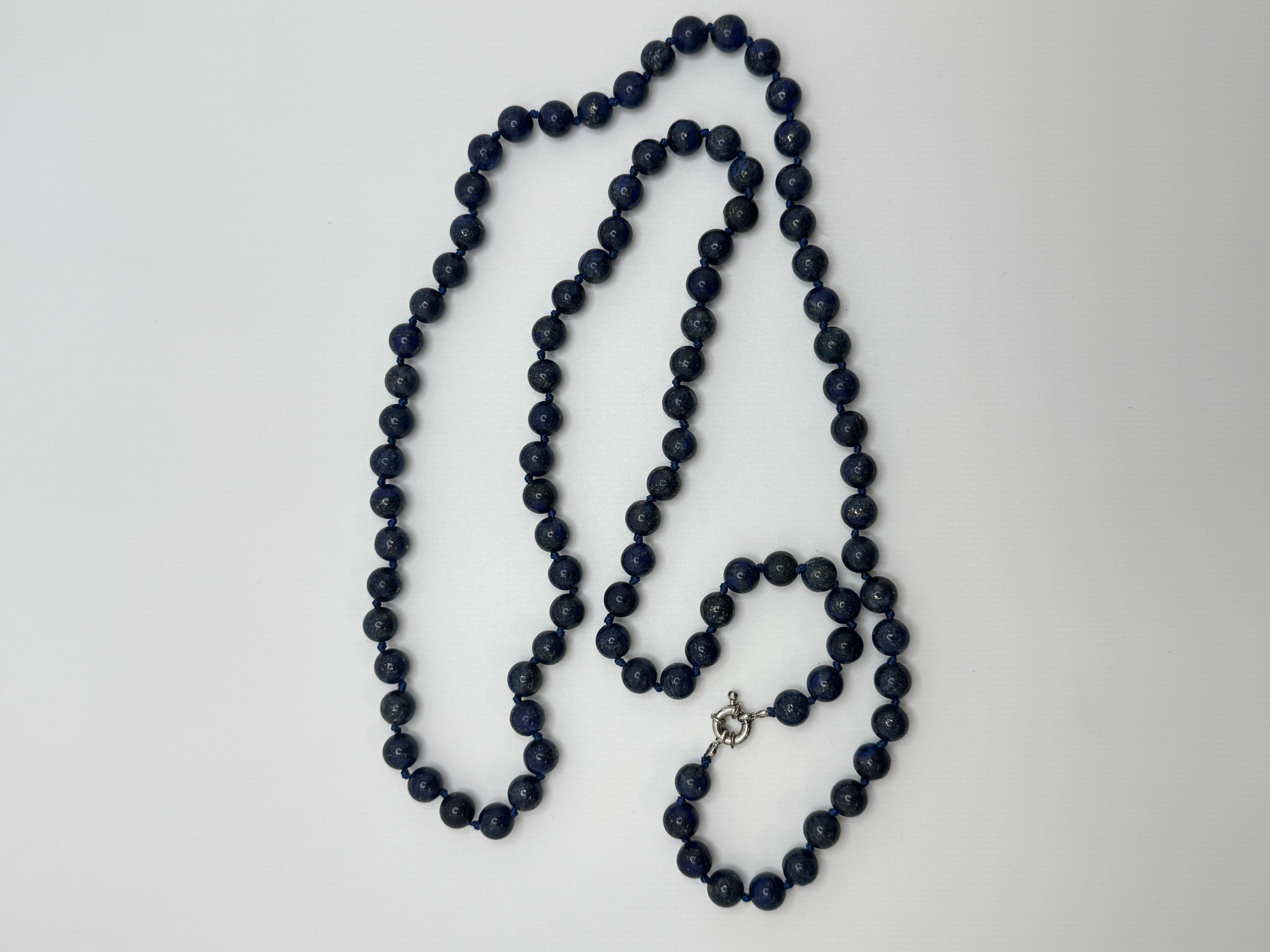 Diese auffällige 38-Zoll-Perlenkette besteht aus 96 tiefblauen Lapislazuli-Perlen, die jeweils etwa 7,0 mm messen. Die Kette ist zwischen den einzelnen Perlen fachmännisch von Hand geknüpft und bringt die natürliche Schönheit und die satte Farbe der