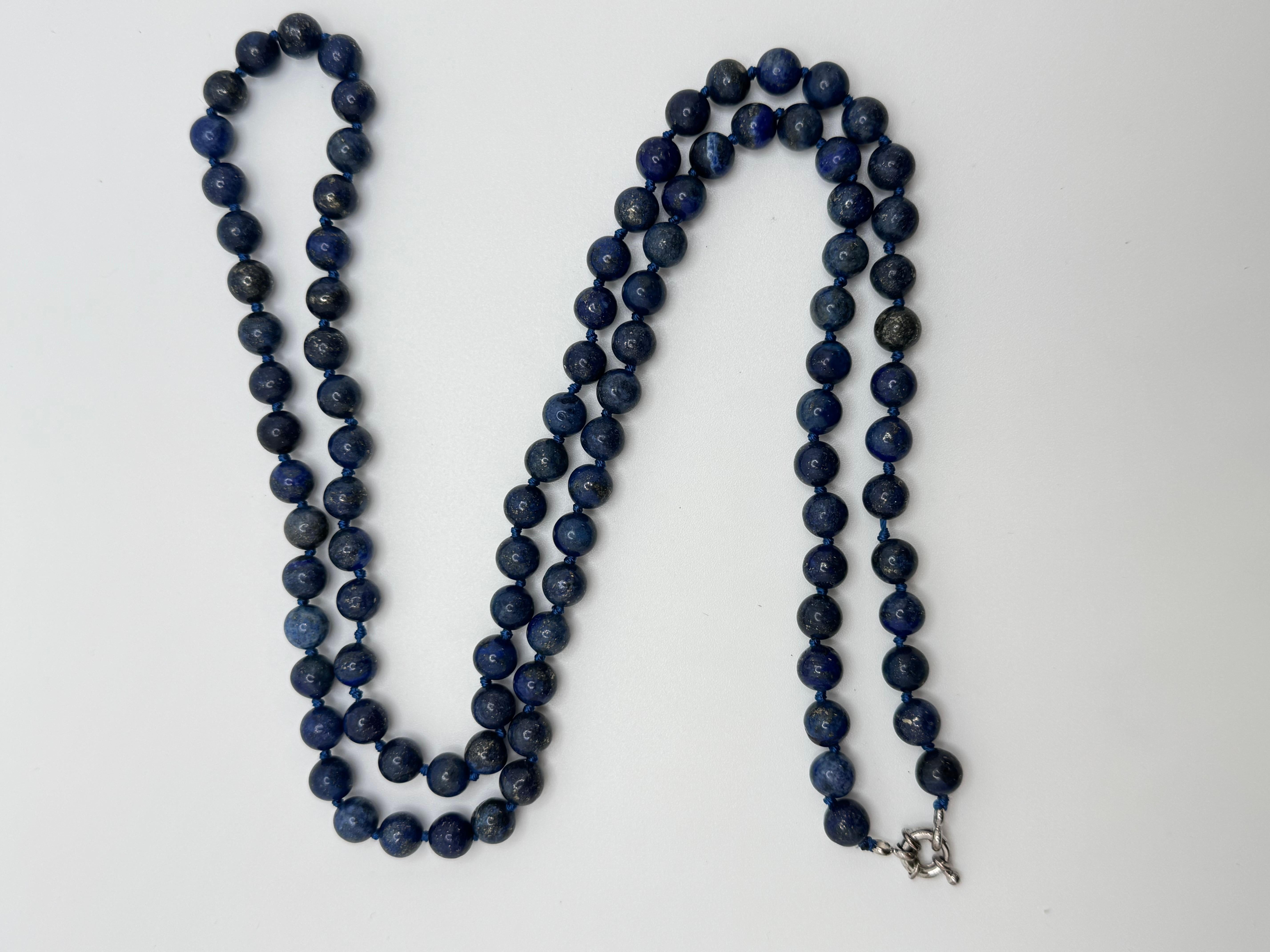 Diese auffällige 36-Zoll-Perlenkette besteht aus 97 tiefblauen Lapislazuli-Perlen, von denen jede etwa 6,5 mm misst. Die Kette ist zwischen den einzelnen Perlen fachmännisch von Hand geknüpft und bringt die natürliche Schönheit und die satte Farbe