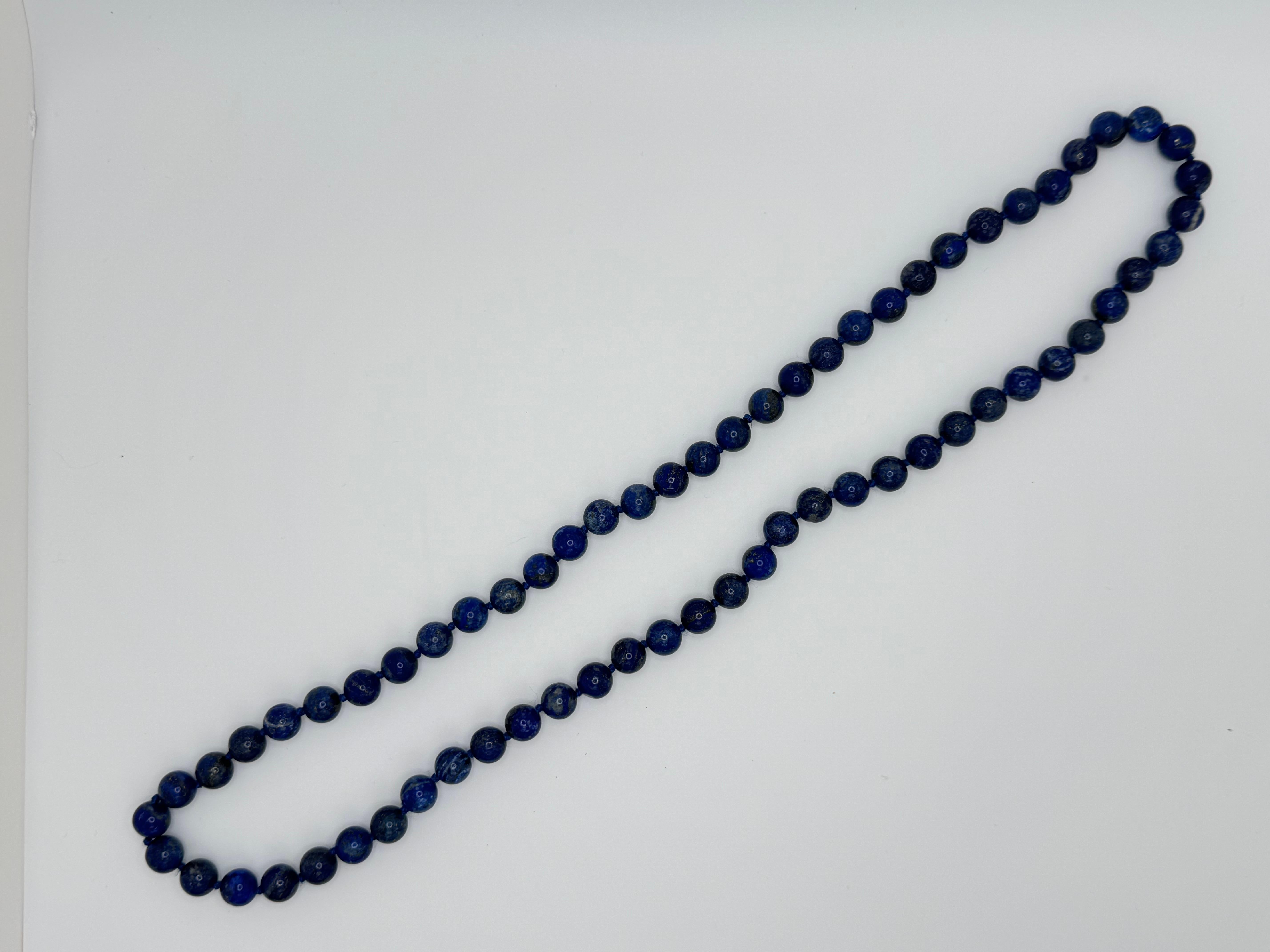 Diese elegante 28-Zoll-Halskette präsentiert 65 sattblaue Lapislazuli-Perlen mit einem Durchmesser von jeweils etwa 9,5 mm. Die Perlen werden einzeln von Hand geknüpft, was sowohl die Haltbarkeit als auch die raffinierte Präsentation der Halskette