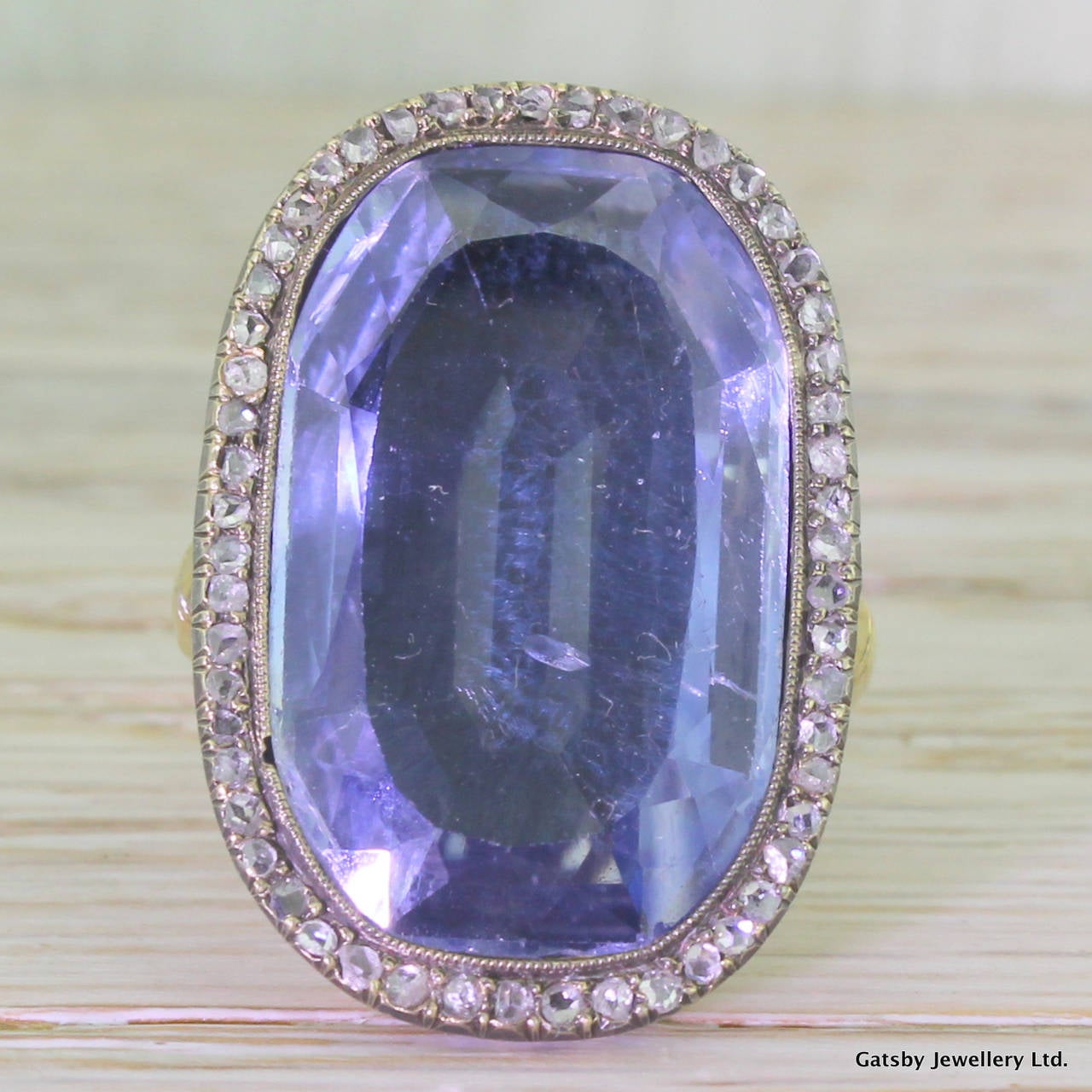 A grand, museum quality ring featuring a veritable boulder of a sapphire. The gorgeous sky blue Ceylon sapphire is natural and unenhanced, weighing in at 25.30 carat. With a halo of 54 rose cut diamonds in the surround, set with milgrain detailing.