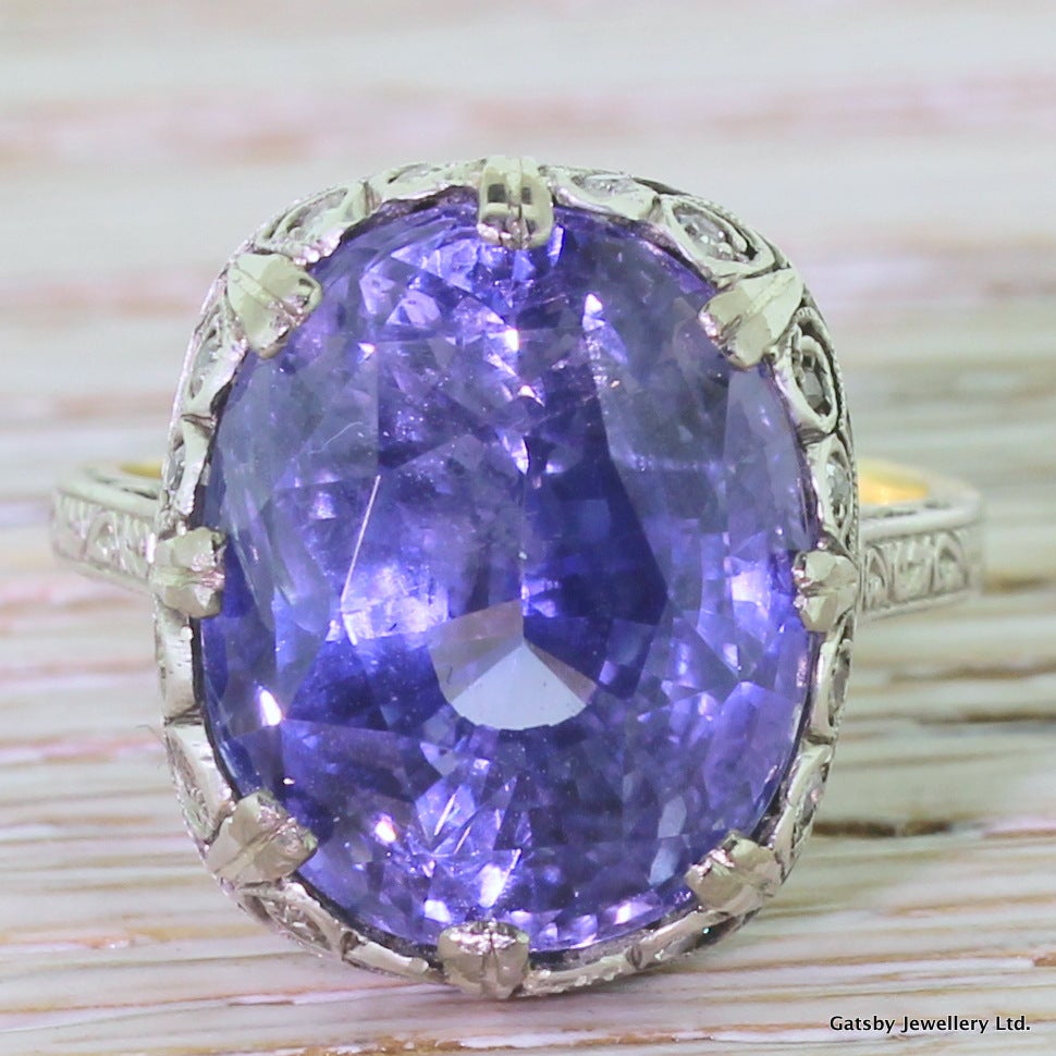 Put simply, a treasure. This quite unbelievable ring features a bright and transparent blue sapphire with flashes of violet. The stone is in the most breathtaking setting; fine intricate scrolling featuring stylised heart motifs in the gallery,