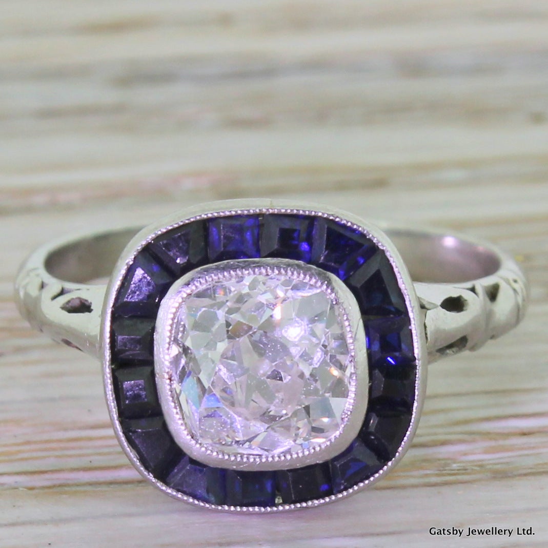 Just... wow. All in platinum and set to centre with an approximate 1.50 carat old cushion cut diamond of the highest quality; clean and high white. The diamond is bezel set with lovely milgrain detail, and then 
