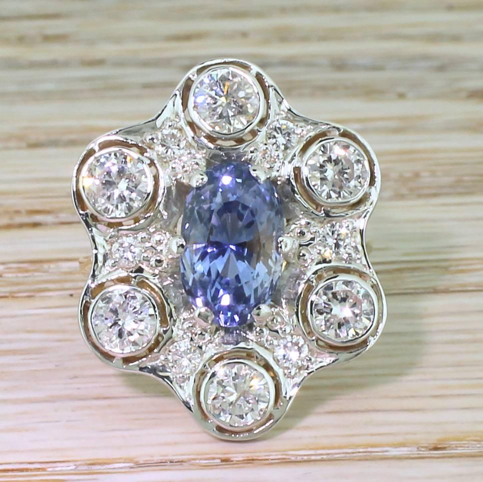 An extraordinary natural sapphire and diamond ring. The natural and unheated Ceylon sapphire is a lively, light cornflower blue and sits at the centre of the most wonderfully flamboyant cluster. Six large rubover set round brilliant cut diamonds