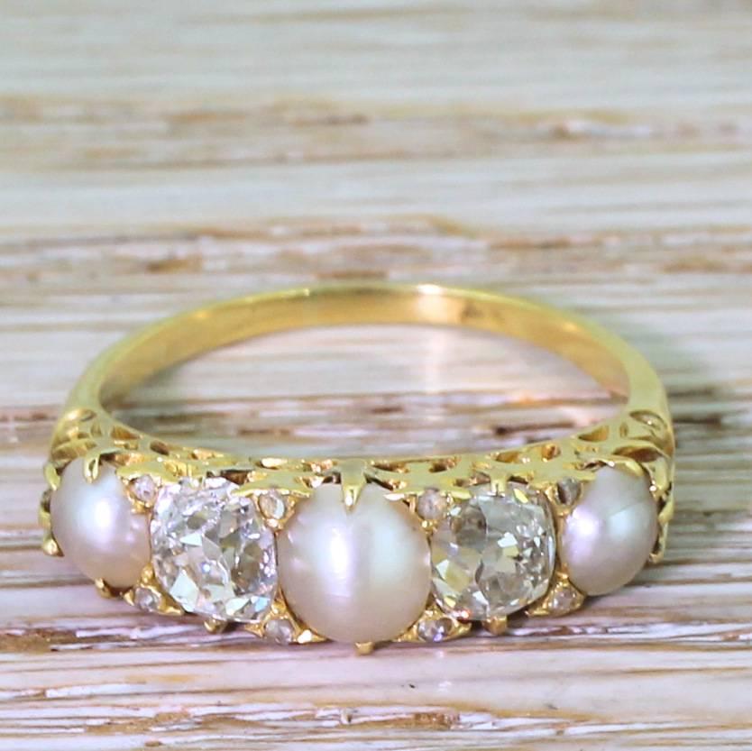An excellent example of a late Victorian carved half hoop ring. Set with three natural split pearls and a pair of bright and lively 0.60 carat (approx.) old cut diamonds within a beautifully carved gallery, to a slim yellow gold shank. Sophisticated