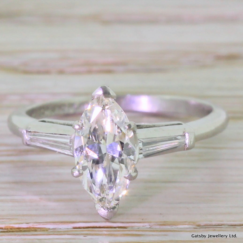 A magnificent marquise cut diamond in an equally magnificent handmade platinum mount. Centred with a bright, vibrant marquise cut diamond. A pair of special cut, elongated tapered baguette cut diamonds are set in the shoulders which leads to a very