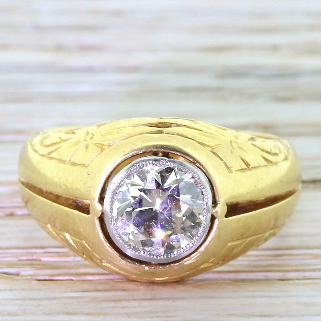 A vibrant old European cut diamond in the most glorious and intricate of gypsy rings. The diamonds is bezel set in white gold and “floats” within the mount. A deep grooves runs all the way around a shank that features fine stylised floral motifs on