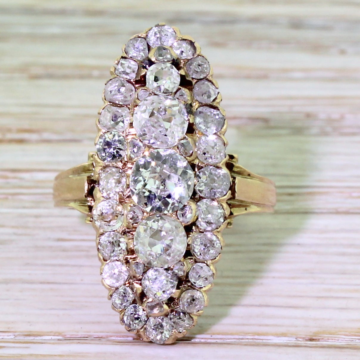 A magnificent late Victorian navette shaped cluster ring, set with an incredible 39 diamonds. The central cluster features five diamonds of graduating size inter-set with ten “spacer” diamonds. A further 24 diamonds encircle this in a graceful long