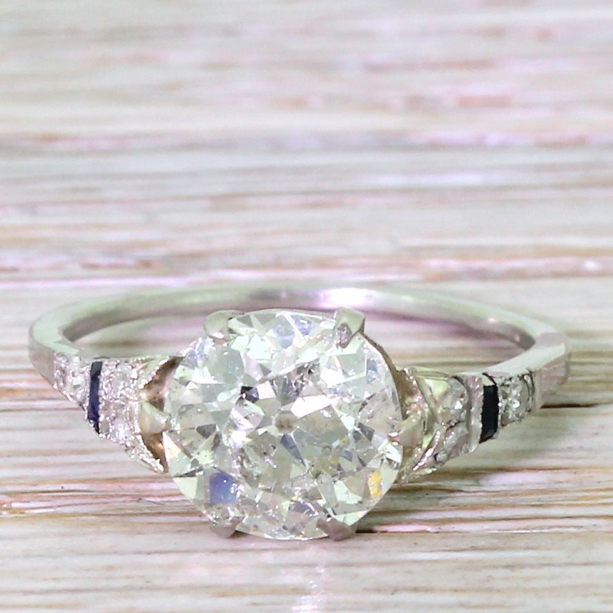 A large chunk of old cut diamond in a fine and delicate platinum mount. The central diamond is eye-catching and envy-inducing, sparkling in even the dimmest of lighting. Set in a fine mount whose graduating shoulders feature three eight diamonds and