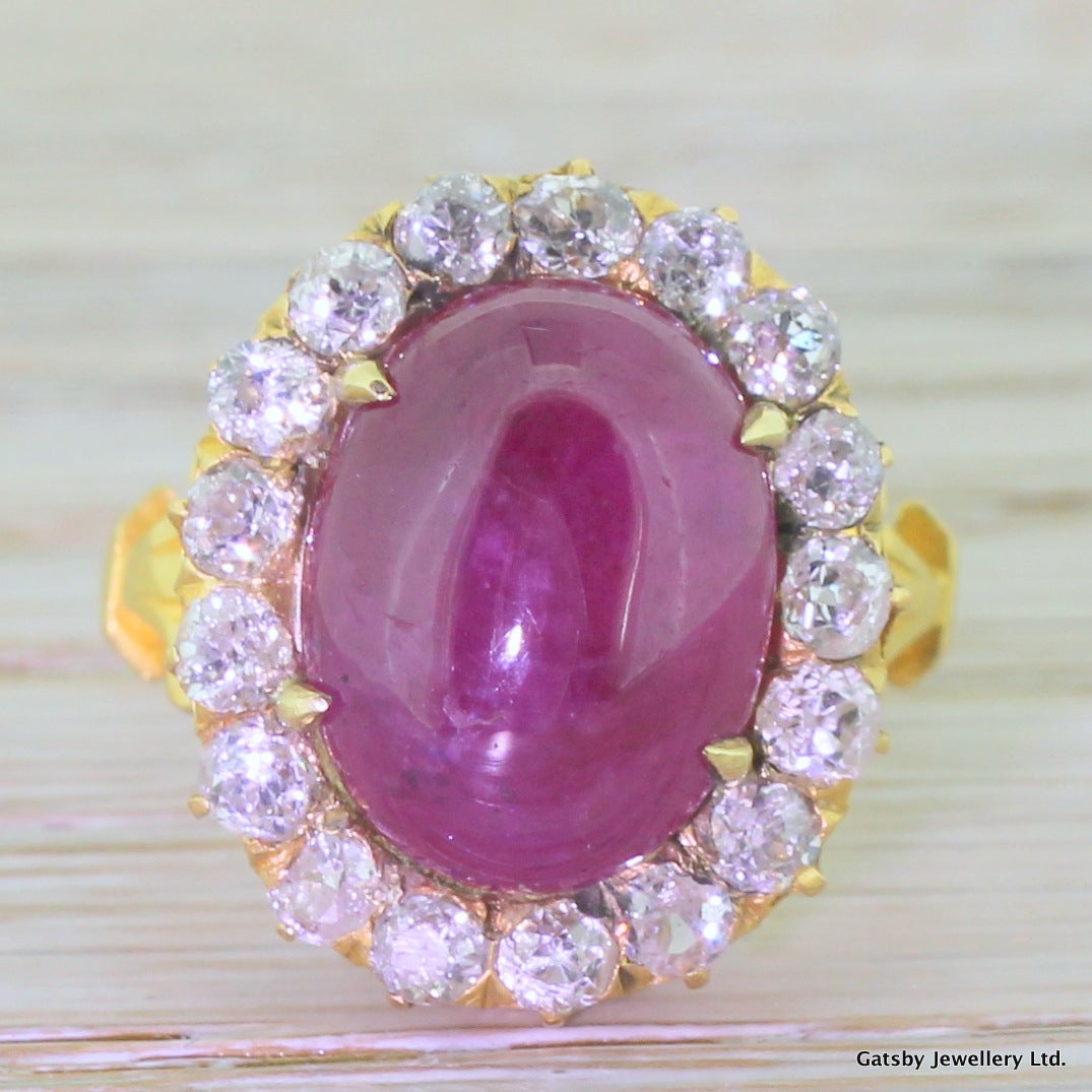 Immense in every sense. This big, bold cluster ring features a fantastic hot-pinkish red cabochon ruby, most likely Afghan in origin. Surrounded by 17 very bright, sparkly and substantial old mine cut diamonds. Set in a high profile peirced gallery
