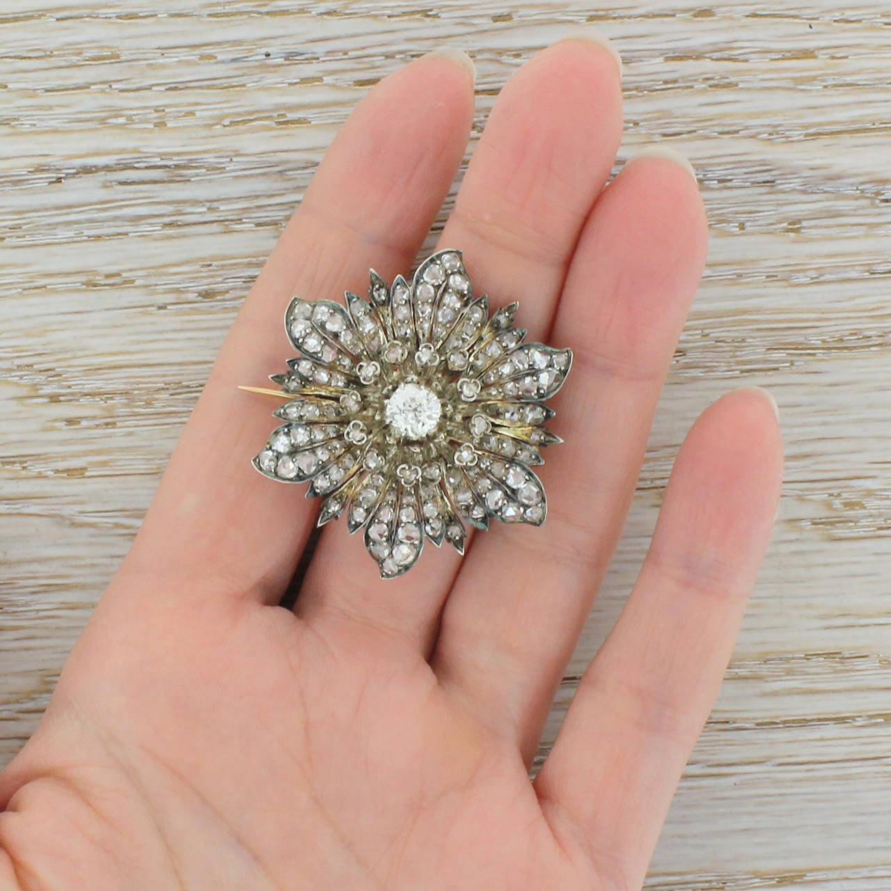 An highly impressive flower brooch; ornate, detailed and exquisitely crafted. Set with 101 rose cut diamonds and centred by one larger old miner cut diamond with a total estimated diamond weight of 2.90 carat. The stones are set in silver with the