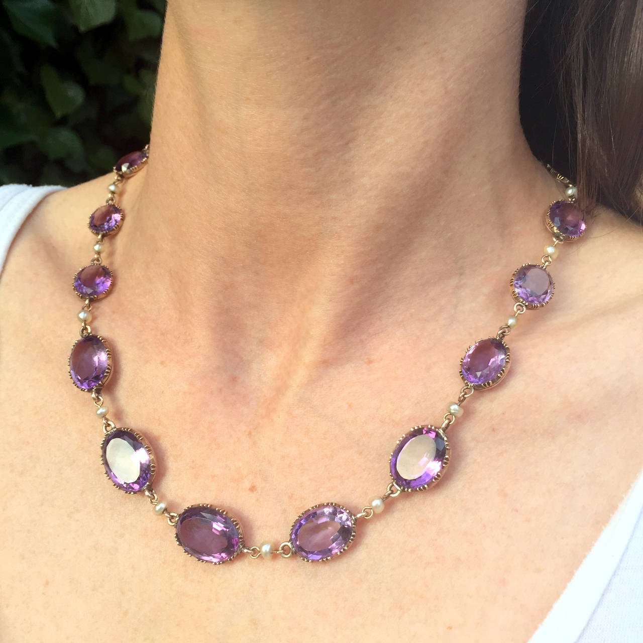 A fine and elegant Victorian riviere necklace, with 19 horizontally set oval cut natural amethysts in an open backed cutdown claw setting, allowing maximum light into these glowing purple stones. The articulated links are each hold a natural seed