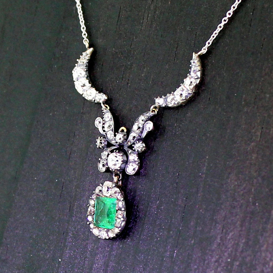 A magnificent pendant necklace. Featuring a square cut Colombian emerald which is surrounded by rose and old mine cut diamonds in a pear shaped drop. The extraordinary finely crafted middle panel resembles, to us, a butterfly. This links to two half