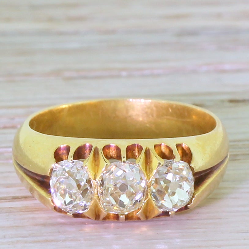 Three gorgeous cushion shaped old mine cuts in this substantial Victorian ring. The diamonds, all of equal shape and proportion, are extraordinarily bright and lively. The open pierced gallery leads to a split shoulder and a chunky D-shaped band. A