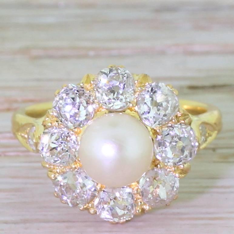 Immensely beautiful. The natural saltwater button pearl is surrounded by eight quarter carat old cut diamonds – all bright white and of high clarity – in an arresting and finely detailed mount. The hand-sawn gallery leads to diamond set fleur de lis