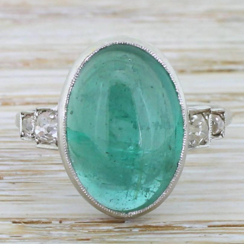 Hypnotically beautiful. The glowing cabochon emerald is gentle blueish green and display very good transparency for a stone of this size. The emerald is rubover and milgrain set above a strikingly geometric gallery, leading to old cut diamond
