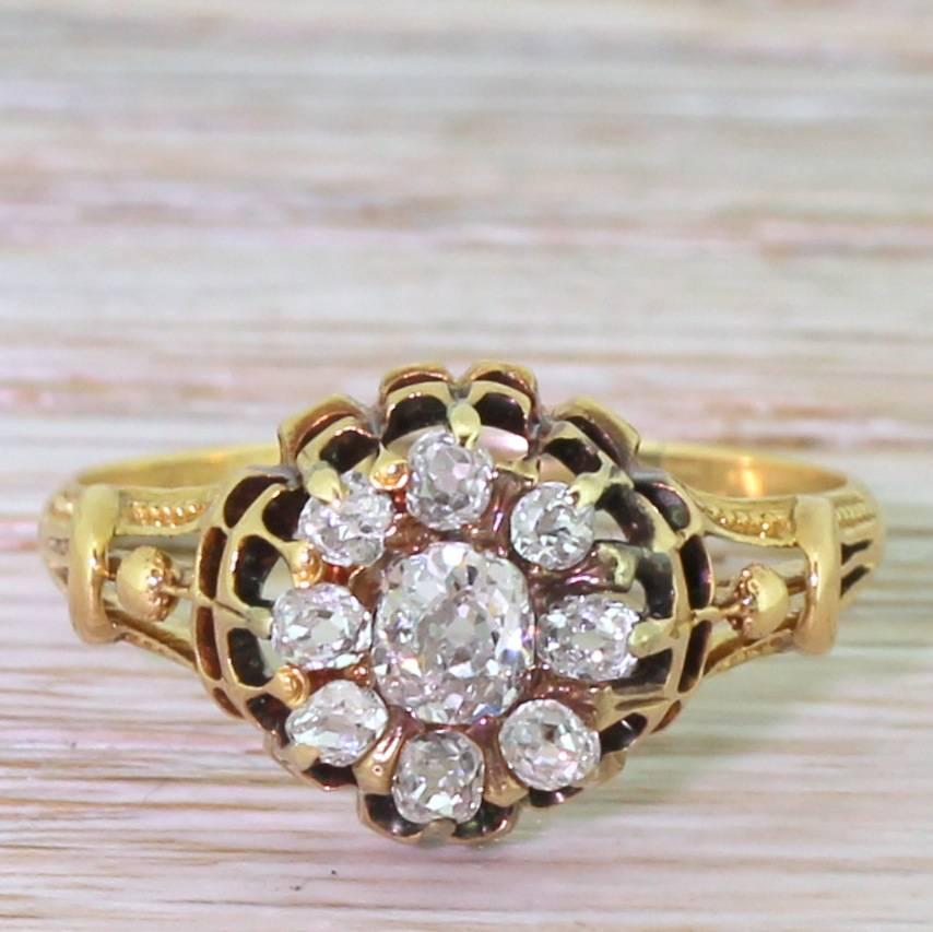 Just marvellous. The cluster features nine high white and sparkly old mine cut diamonds in a daisy / target formation. The finely hand-sawn double gallery to a beautiful detailed split shoulder band. A dainty and delightful one-0ff.

Cut – Old