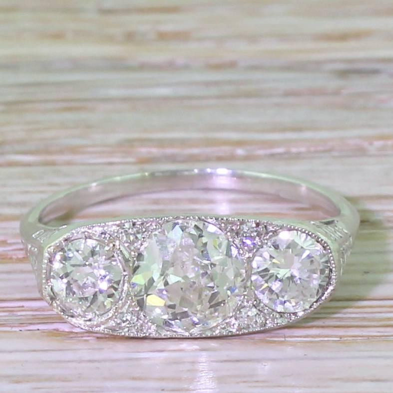 A crisp and classy three stone ring with an approximate 1.10 carat old cut diamond flanked by a pair of 0.40 carat stones. The three main diamonds are inter-set with four small spacing stones, making the head of the ring an unbroken block of blink.