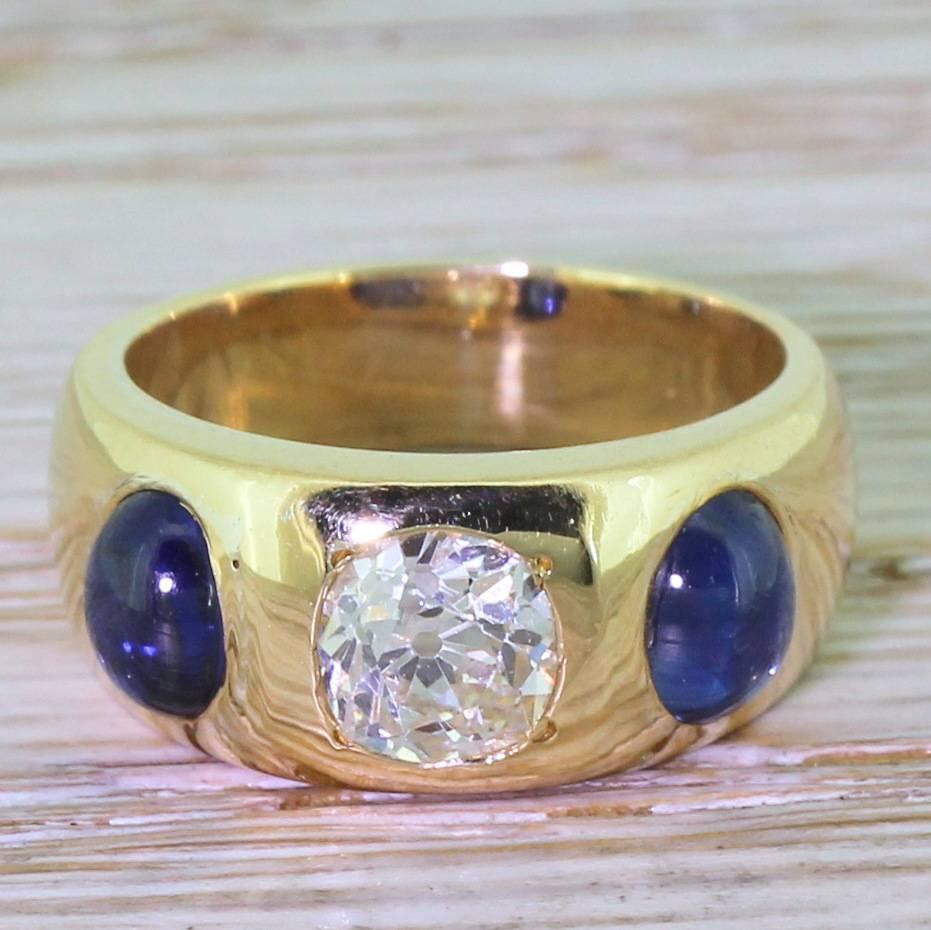 An incredibly white and clear old mine cut diamond flanked by a pair of royal blue cabochon sapphires is a classic gypsy style setting. This is a top grade example of a popular Victorian style with high class stones and a satisfyingly hefty mount.