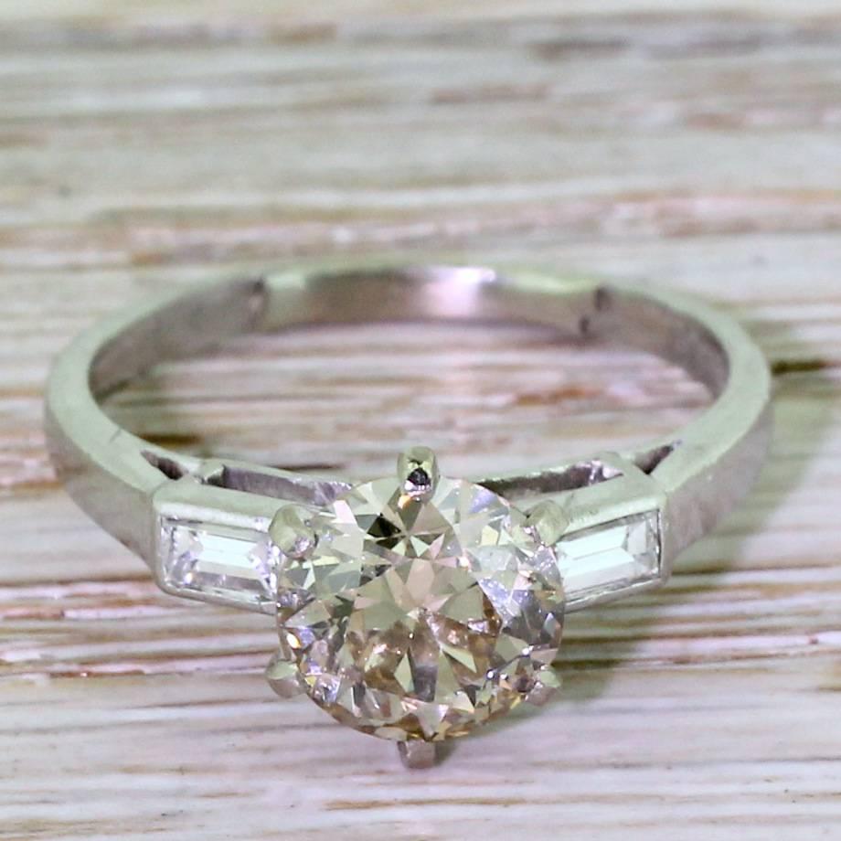 A real statement of an engagement ring. The fancy light cognac diamond displays a soft, almost peachy hue and is set in a six claw collet. The open gallery allow the maximum amount of light into the vibrant stone, and leads to two high white