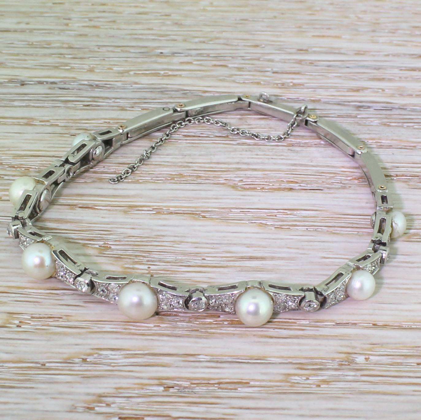 A sumptuous vintage bracelet. Each of the seven main links gently graduates towards a natural saltwater pearl, which is flanked by six (three either side) old eight-cut diamonds. Six rubover set old cuts sit between each of the pearl-set links, with