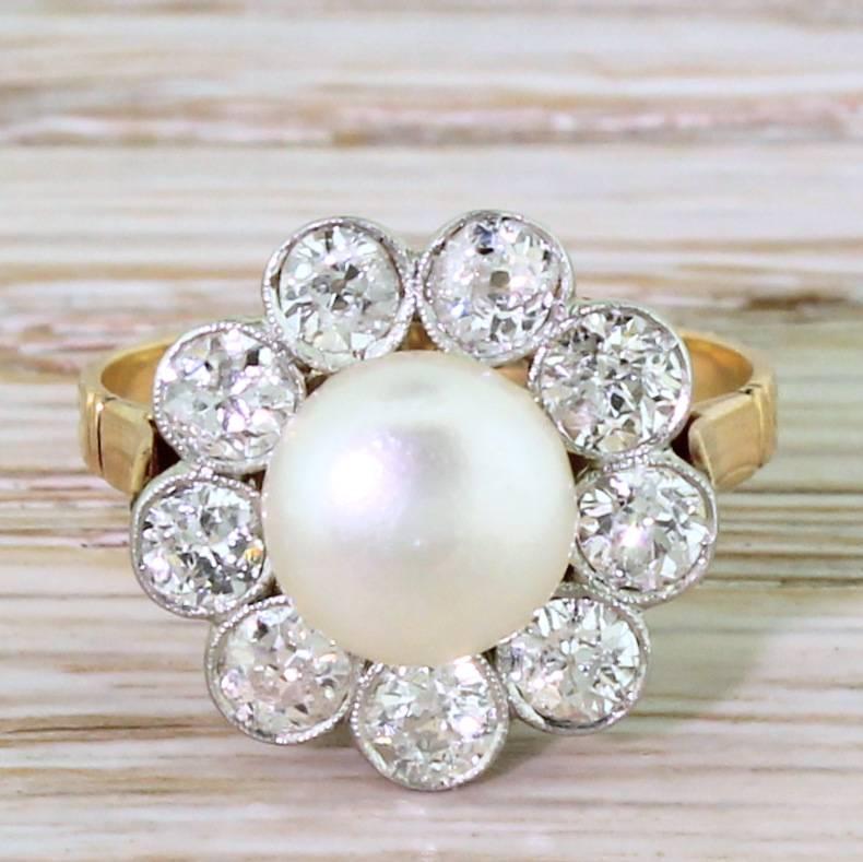A dream of a ring. The wonderfully shaped natural button pearl has a lovely creamy lustre with nine high white old cut diamonds – each one rubover and milgrain set in platinum – sit around the centre gem. The pretty rose gold gallery with hooped