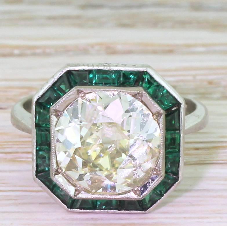 Divine. Internally very clean and alive with fire and brilliance, the very impressive old cut diamond displays a soft and subtle champagne hue. Twenty calibré cut emeralds surround the centre stone in an octagonal setting, with beautiful heart