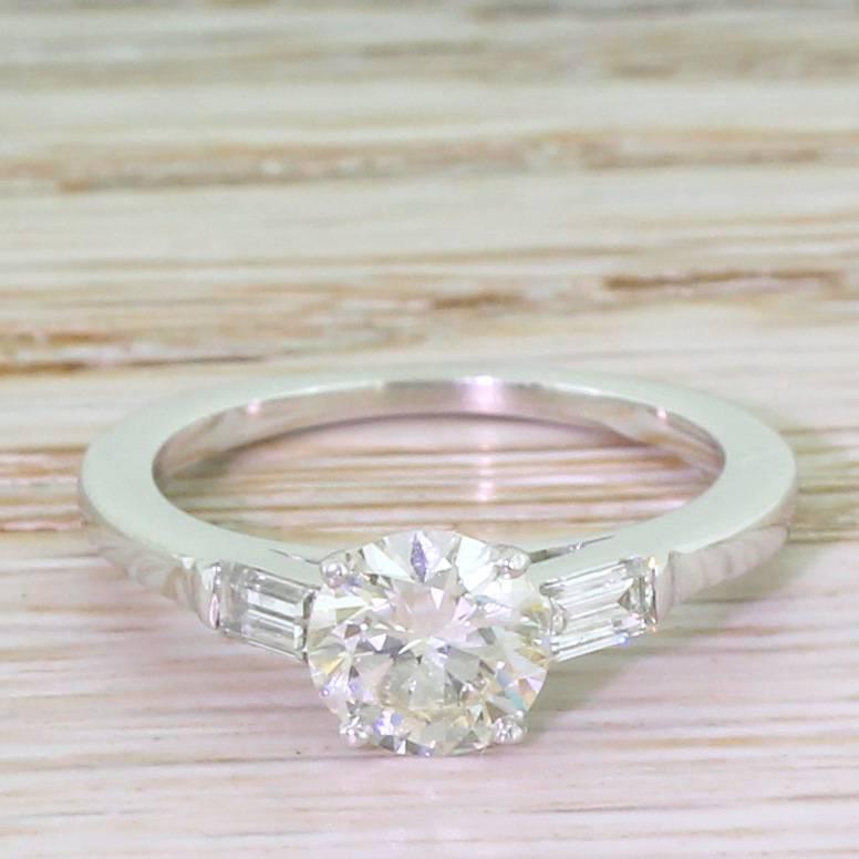 A stunning solitaire engagement ring. The high white and very clean transitional cut diamond is phenomenally lively and vibrant. Each shoulder is adorned with a baguette cut diamond, leading to a nicely substantial D-shaped shank. A classic.

Cut