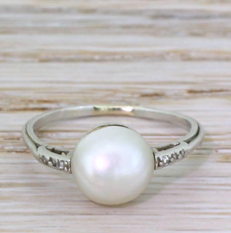 A spectacular natural saltwater pearl. The button shaped pearl displays a gorgeous creamy lustre and is showcased in a slim and understated white gold setting. Six (three either side) rose cut diamonds adorn the shoulders. A stunner.

Accompanied by