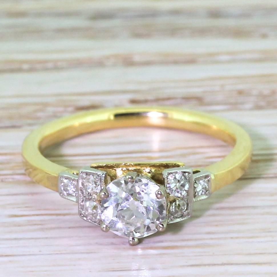 A majestic solitaire engagement ring. The 0.77 carat old mine cut diamond is white, bright and full of life. The centre stone is held in a six-claw collet, and is flanked either side by three diamonds in box settings that step down to a solid
