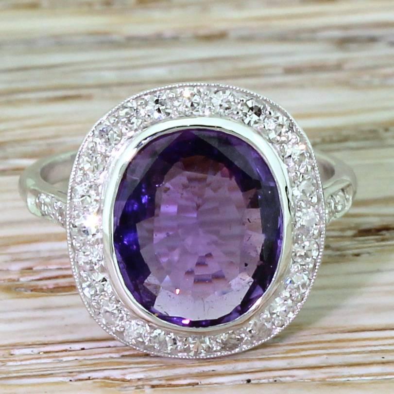 A rich and regal sapphire – natural, unheated and displaying a gorgeous purple hue. The sapphire is rubover set in white gold with twenty-four high white and clean eight-cut diamonds in the surround, and a further six (thee either side) in the